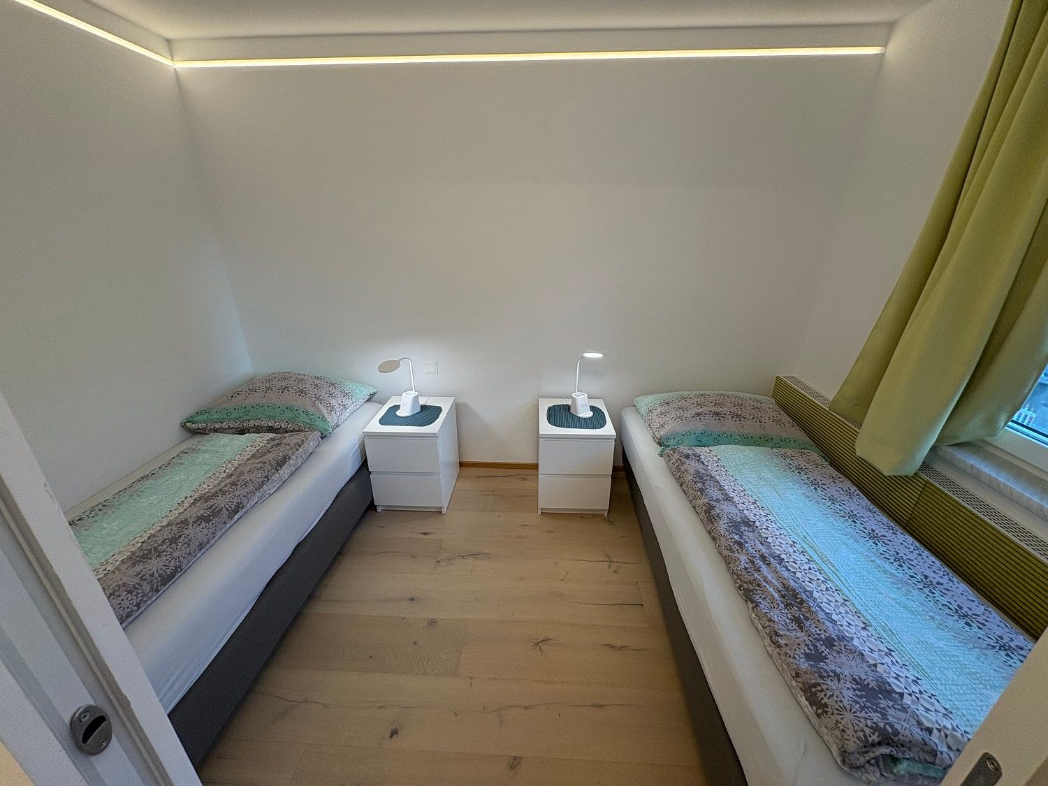 Schlafzimmer mit zwei Einzelbetten, Nachttisch und Lampen.