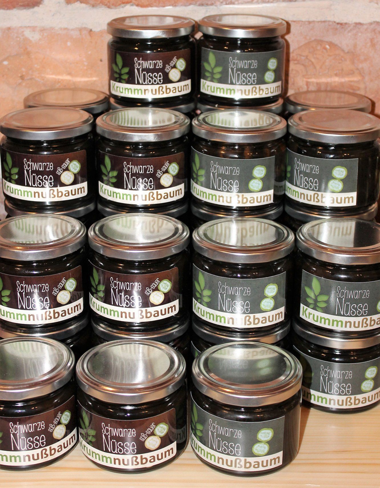 Mehrere Gläser mit der Aufschrift 'Schwarze Nüsse Krummnußbaum' auf einem Tisch gestapelt.