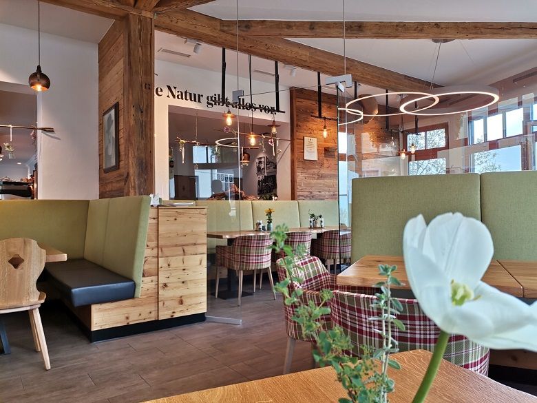 Innenansicht einer gemütlichen Bäckerei mit Holzmöbeln und modernen Leuchten.