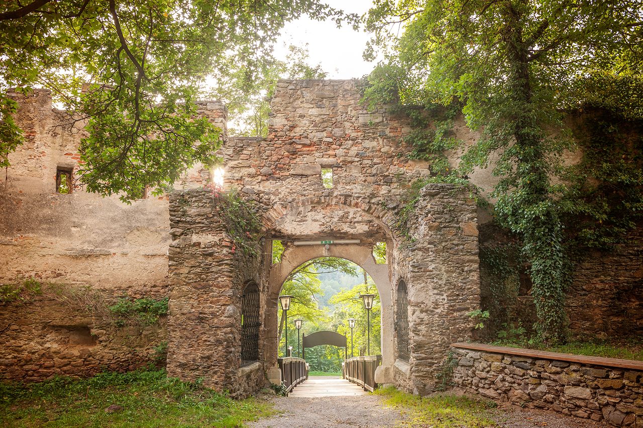 Eingangstor der Burg Gars, umgeben von alten Steinmauern und grüner Vegetation.