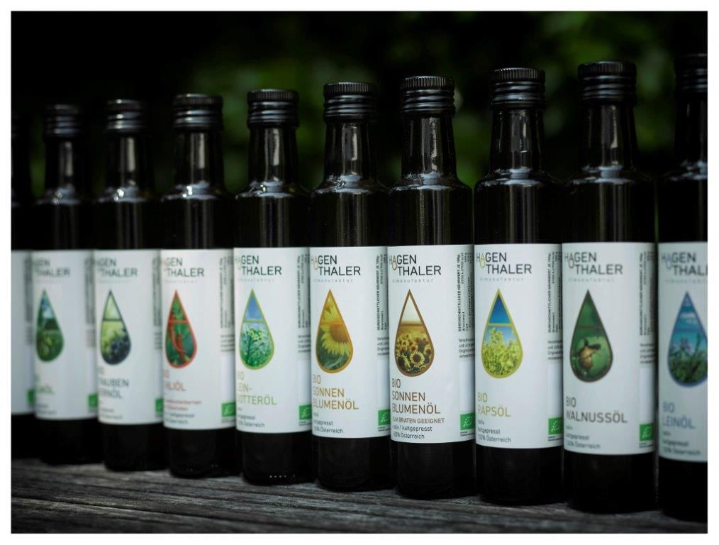 Reihe von Hagenthaler Ölflaschen auf einem Holztisch.