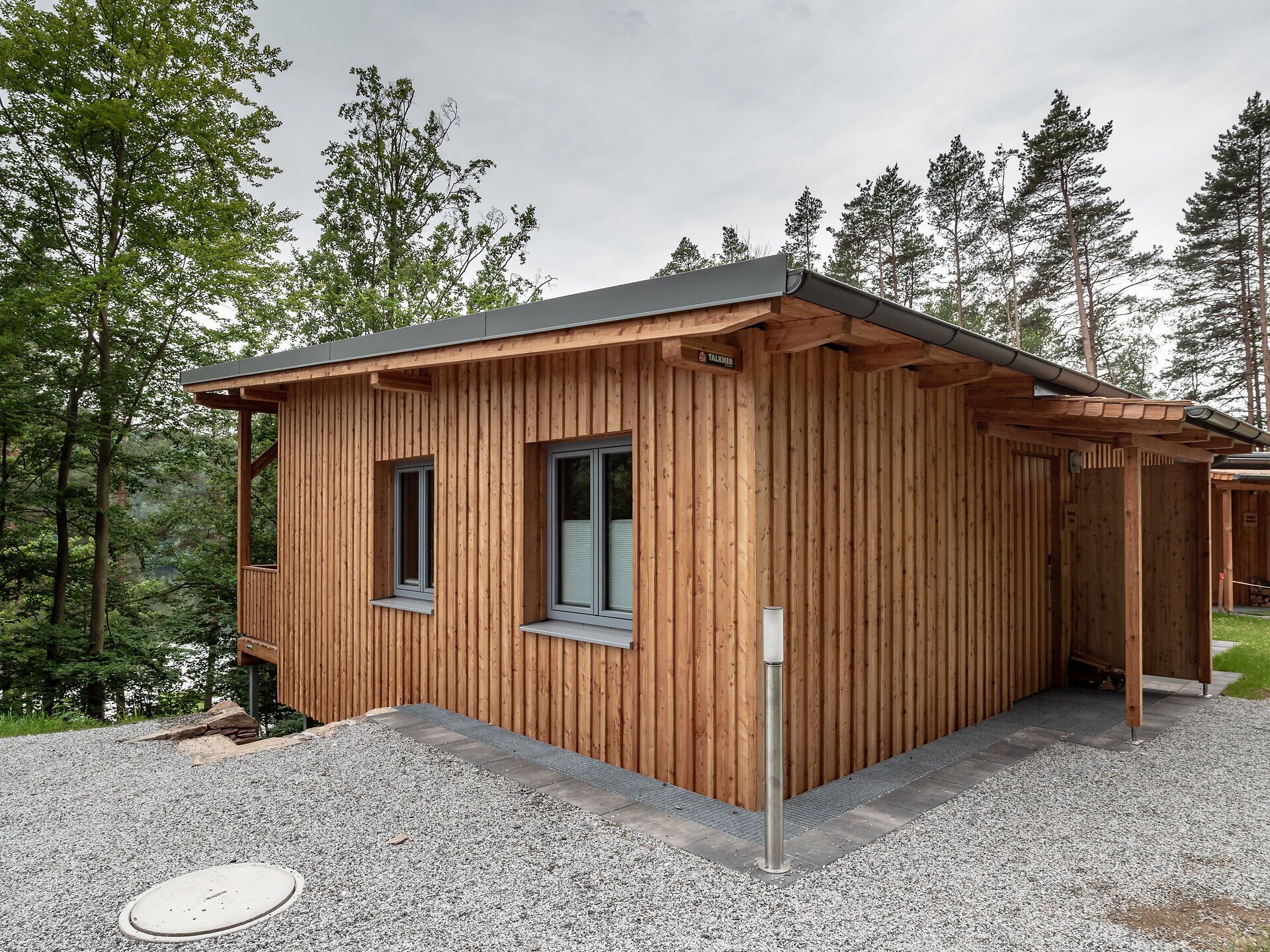 Umgeben von üppigem Grün und majestätischen Bäumen strahlt das charmante Holzhaus eine einladende Wärme aus. Die ruhige Atmosphäre lädt dazu ein, die Seele baumeln zu lassen und die Schönheit der Natur in vollen Zügen zu genießen.