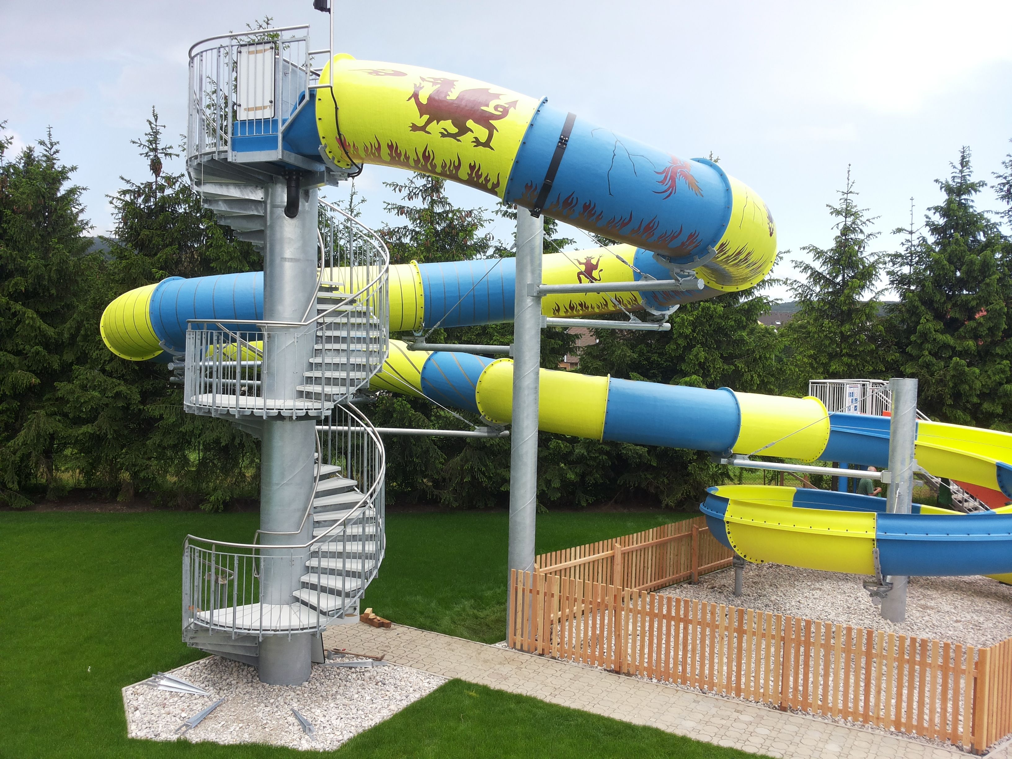 Große Wasserrutsche mit blauen und gelben Röhren und Wendeltreppe.