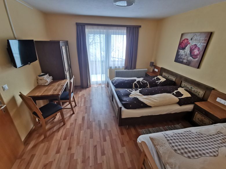 Gemütliches Schlafzimmer mit Doppelbett, Tisch, Stühlen und Balkonzugang.