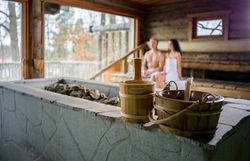 Modernes Hotelzimmer mit Doppelbett, Naturbild an der Wand, Sessel, Tisch und Stehlampe.