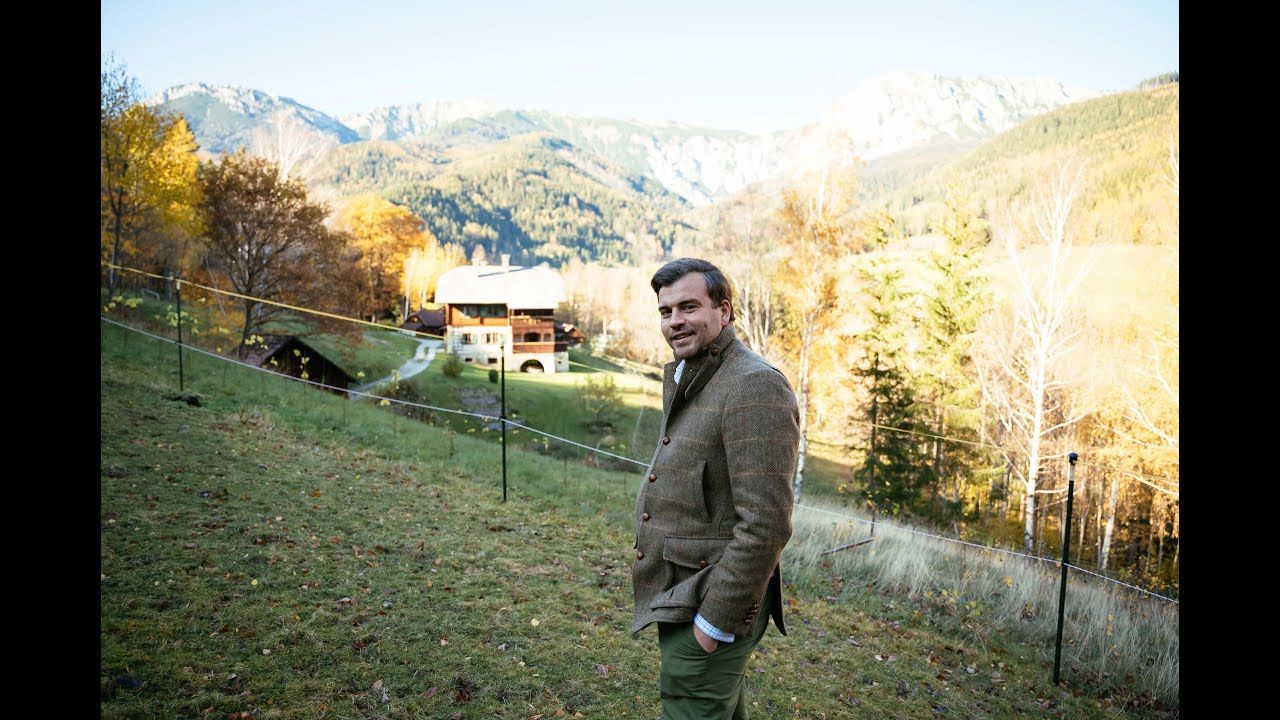 Mann steht auf einer Wiese und lacht in die Kamera