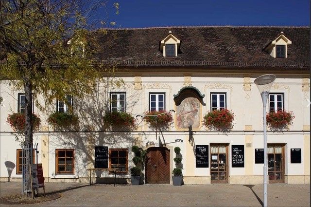 Historisches Gebäude mit Blumenkästen und Wandgemälde.