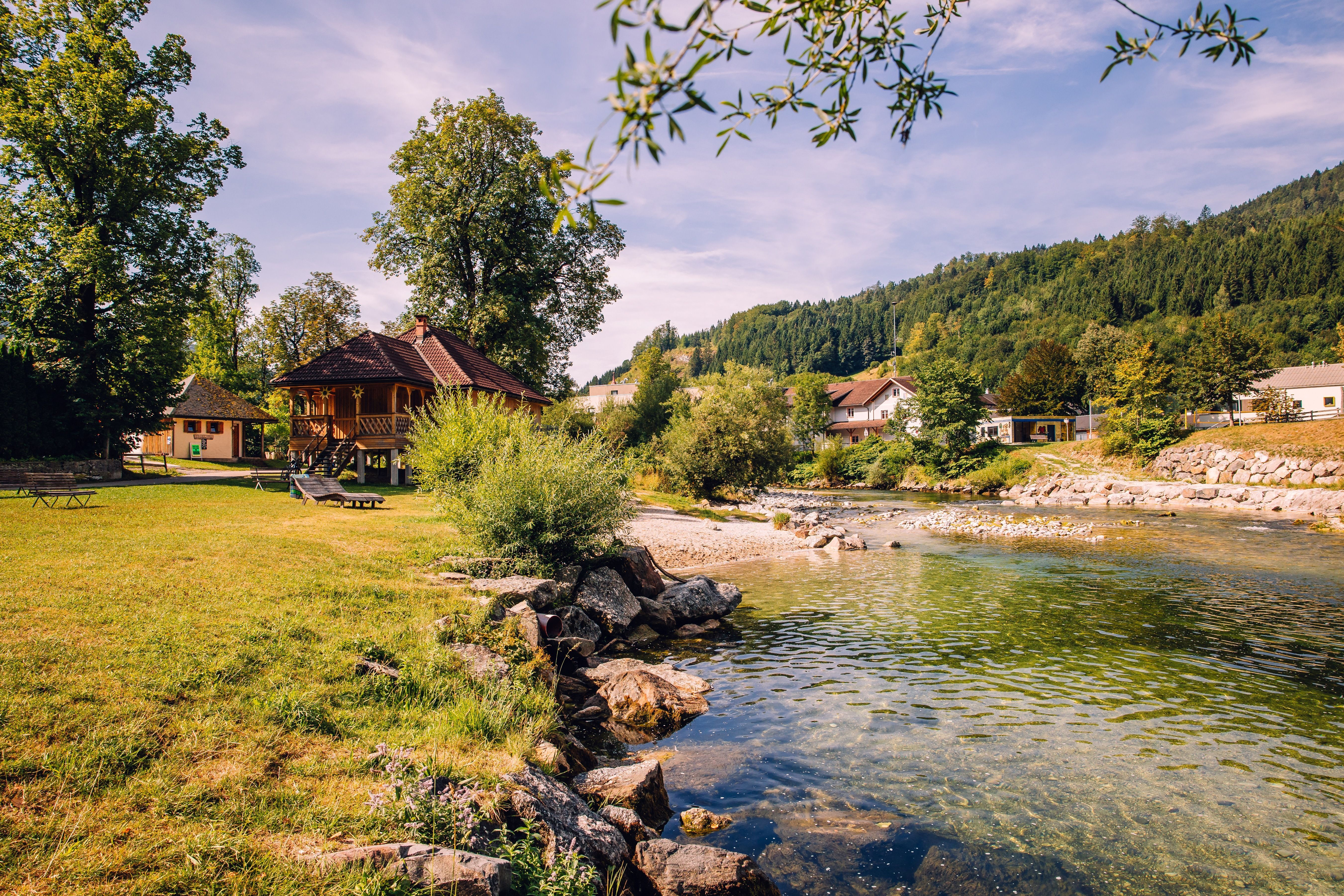 Flussbad an der Ybbs in Göstling mit Wiesen, Bäumen und einem Holzhaus vor bewaldeten Hügeln.
