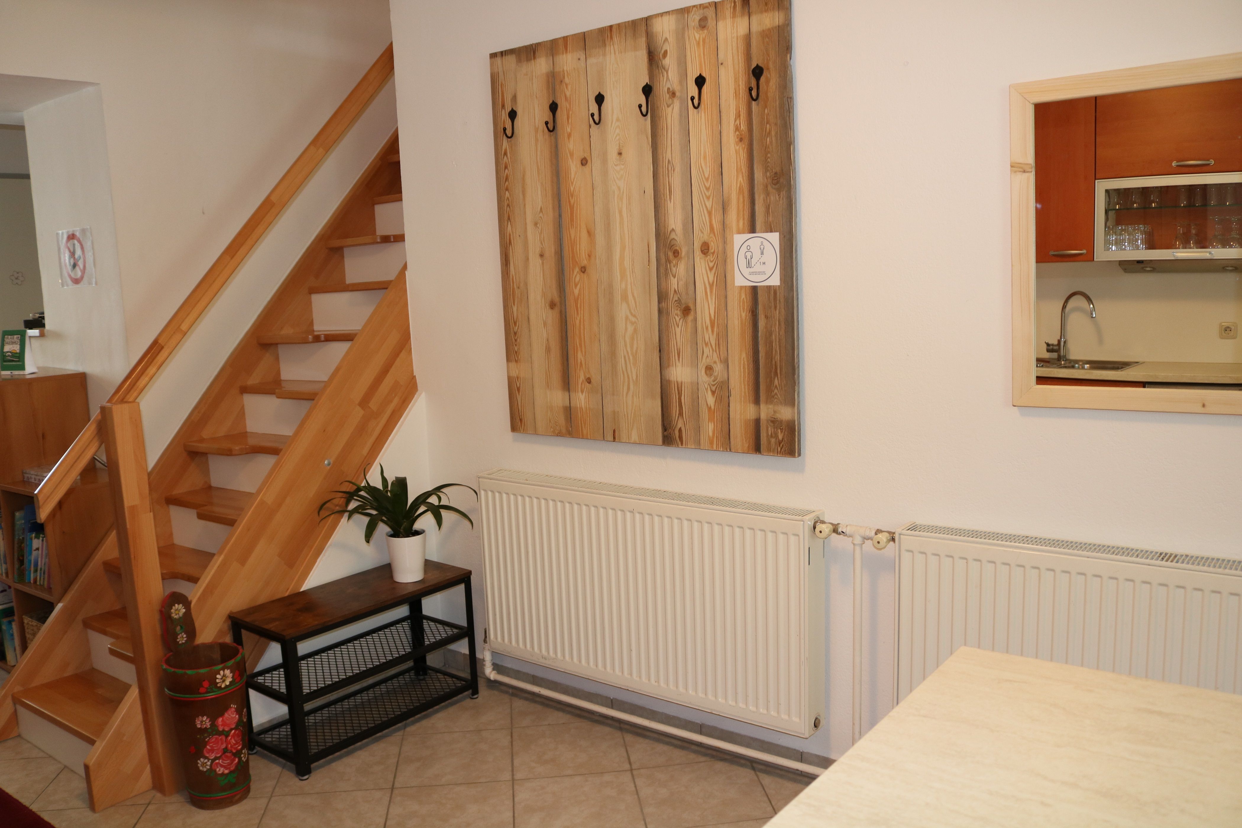 Innenraum mit Holztreppe, Garderobe, Pflanze und Küchenfenster.