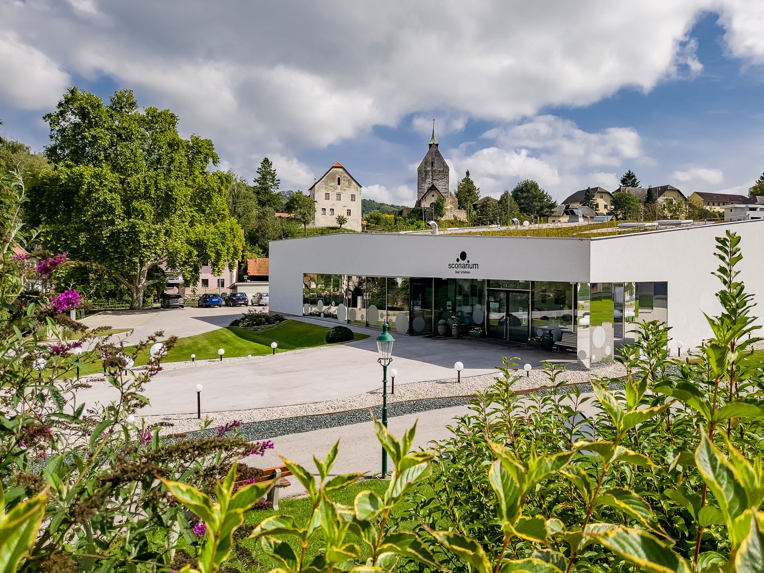 Modernes Gebäude des Sconariums mit Kirche im Hintergrund.