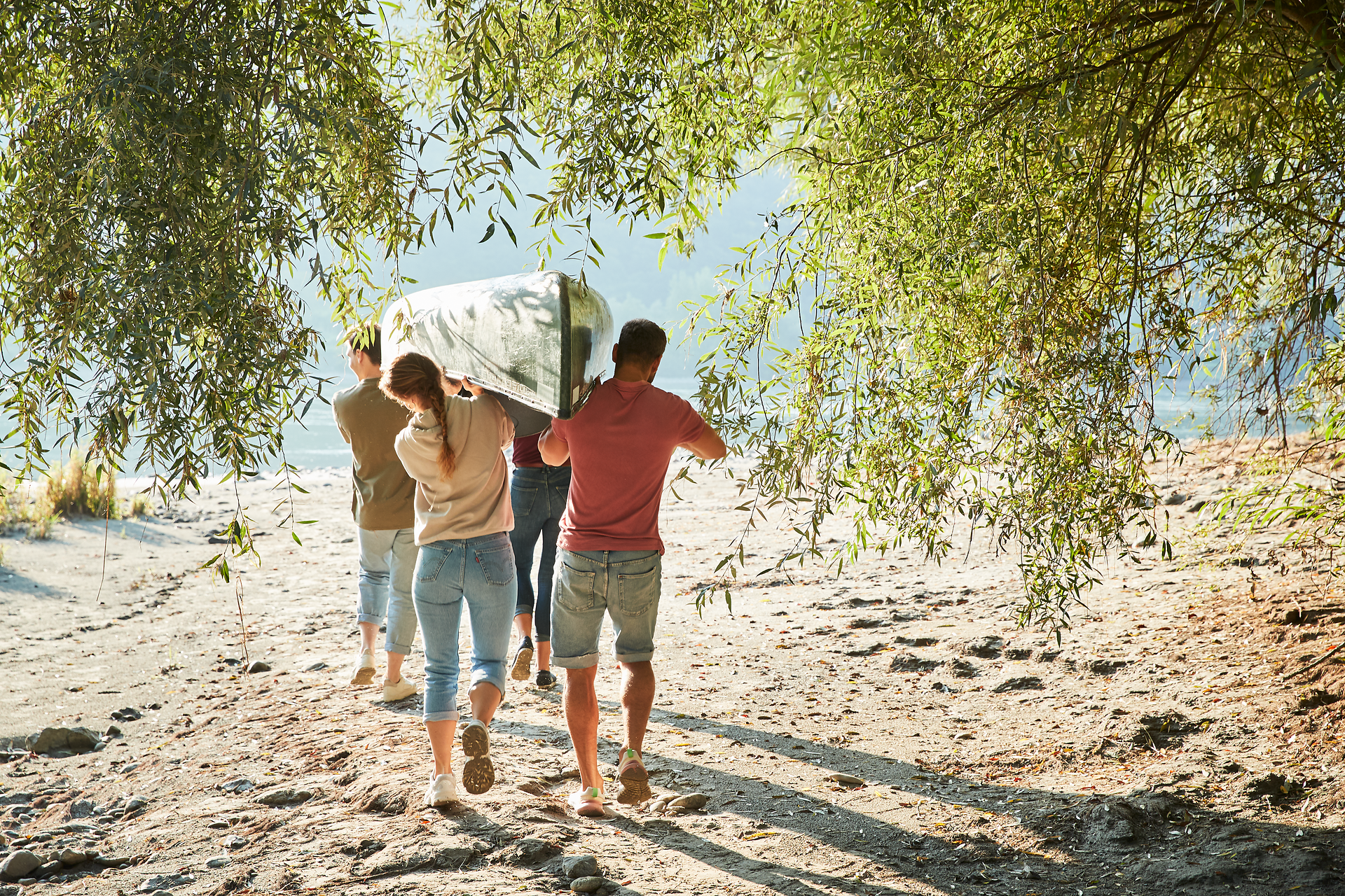 Zwei Personen und ein Hund in einem grünen Kanu auf einem Fluss.