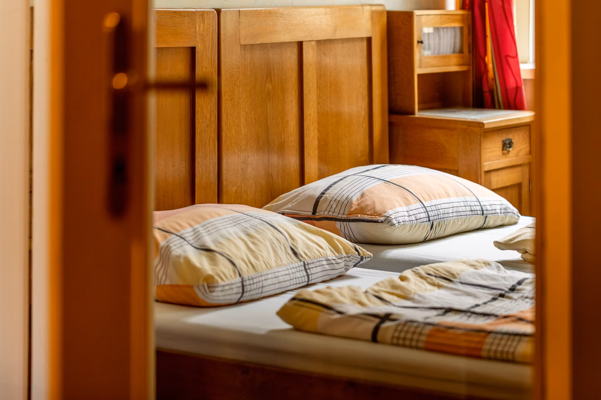 Ein gemütliches Schlafzimmer mit Holzmöbeln und karierten Kissen auf dem Bett.