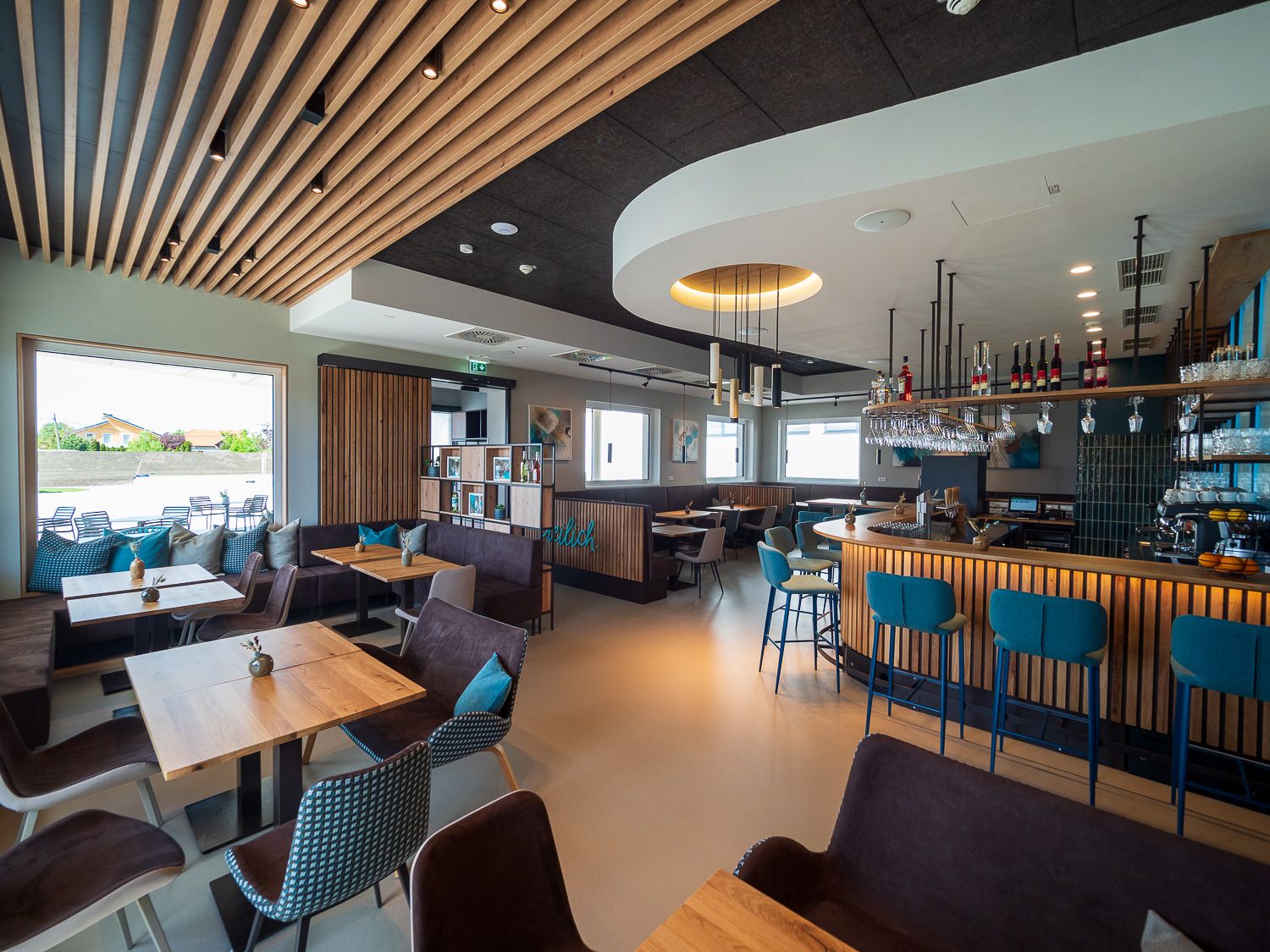 Modernes Bistro mit Holzmöbeln, Bar und großen Fenstern.