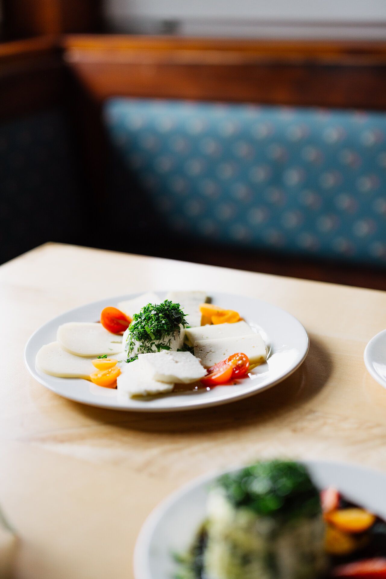 Ein köstlicher Teller mit frisch zubereitetem Schafkäse, garniert mit frischen Kräutern und buntem Gemüse, lädt zum Genießen ein. Die harmonische Kombination aus Aromen und Farben verspricht ein unvergessliches Geschmackserlebnis inmitten der malerischen Landschaft der Wiener Alpen.