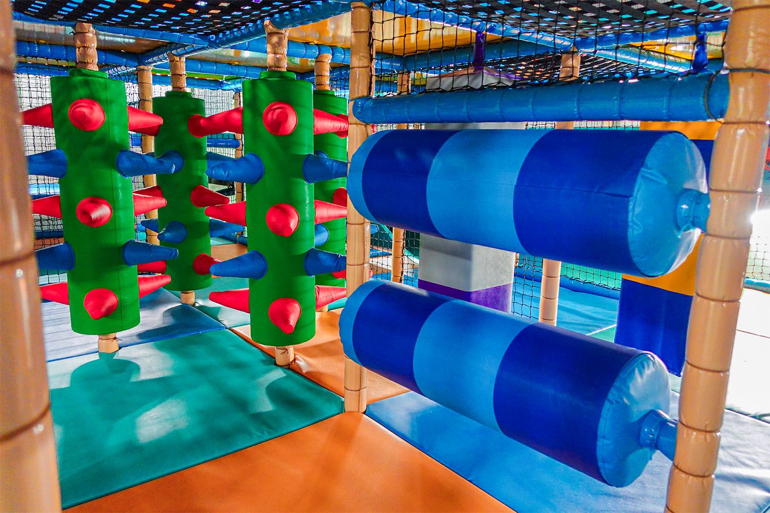 Bunte Spielplatzstruktur mit grünen und blauen Hindernissen.