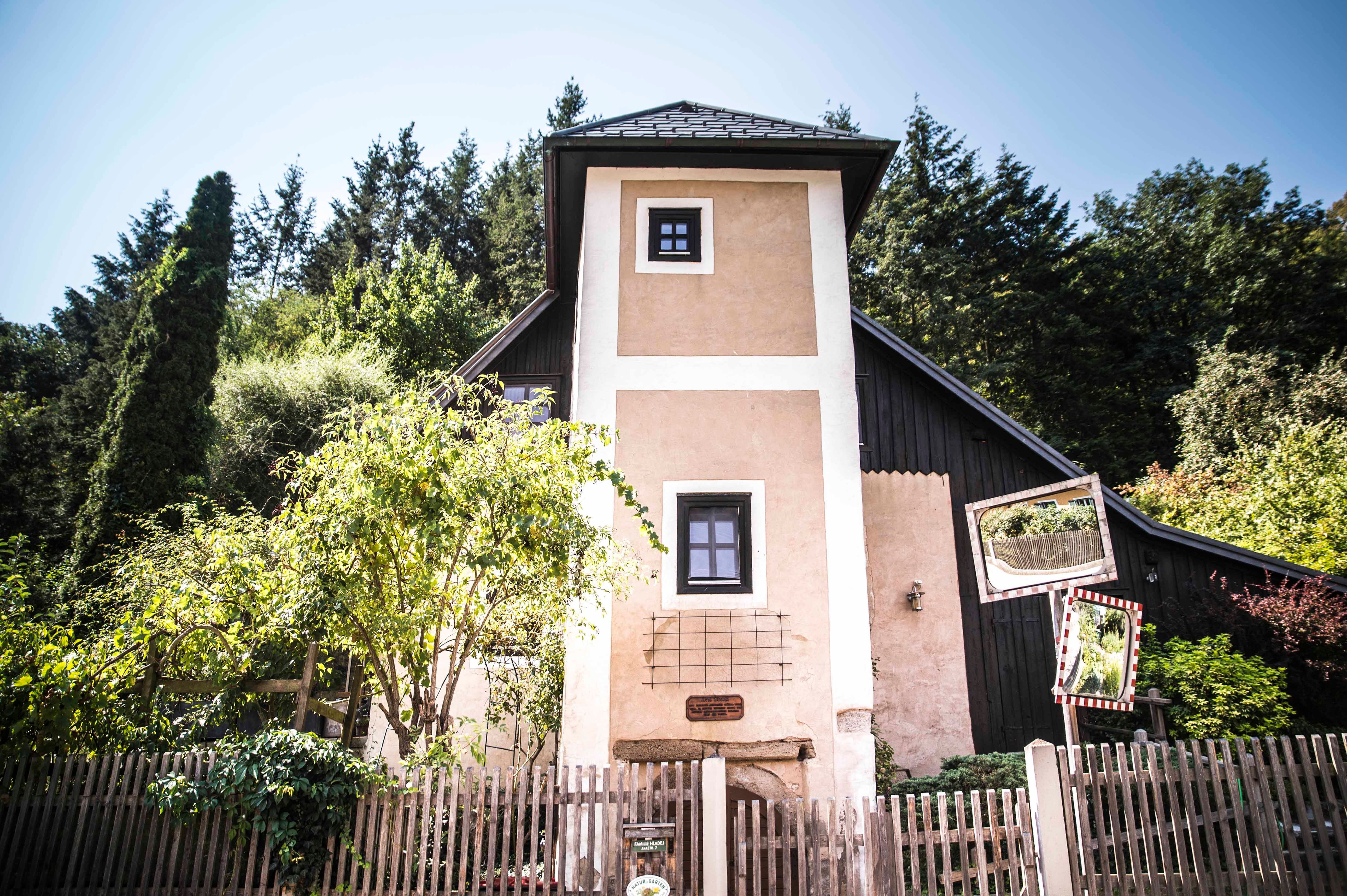 Ein kleiner Turm mit Holzzaun und Bäumen im Hintergrund.