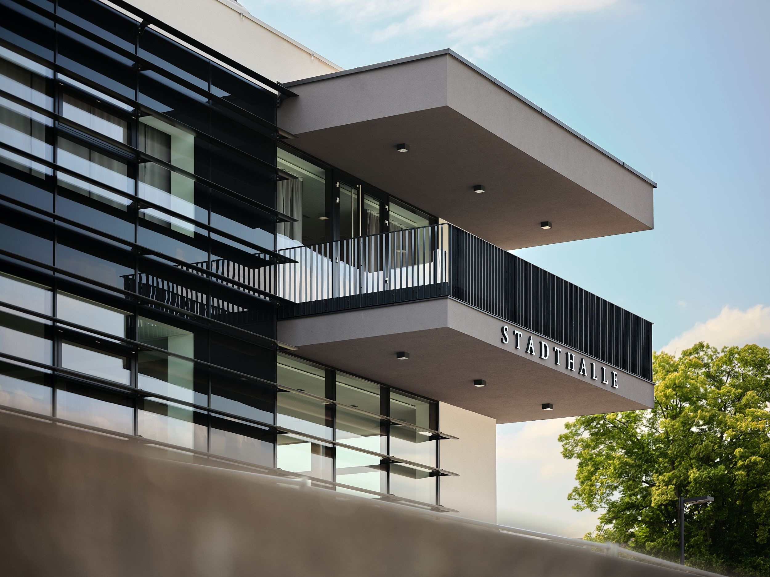 Moderne Außenansicht der Stadthalle Ybbs mit Glasfassade und Balkon.