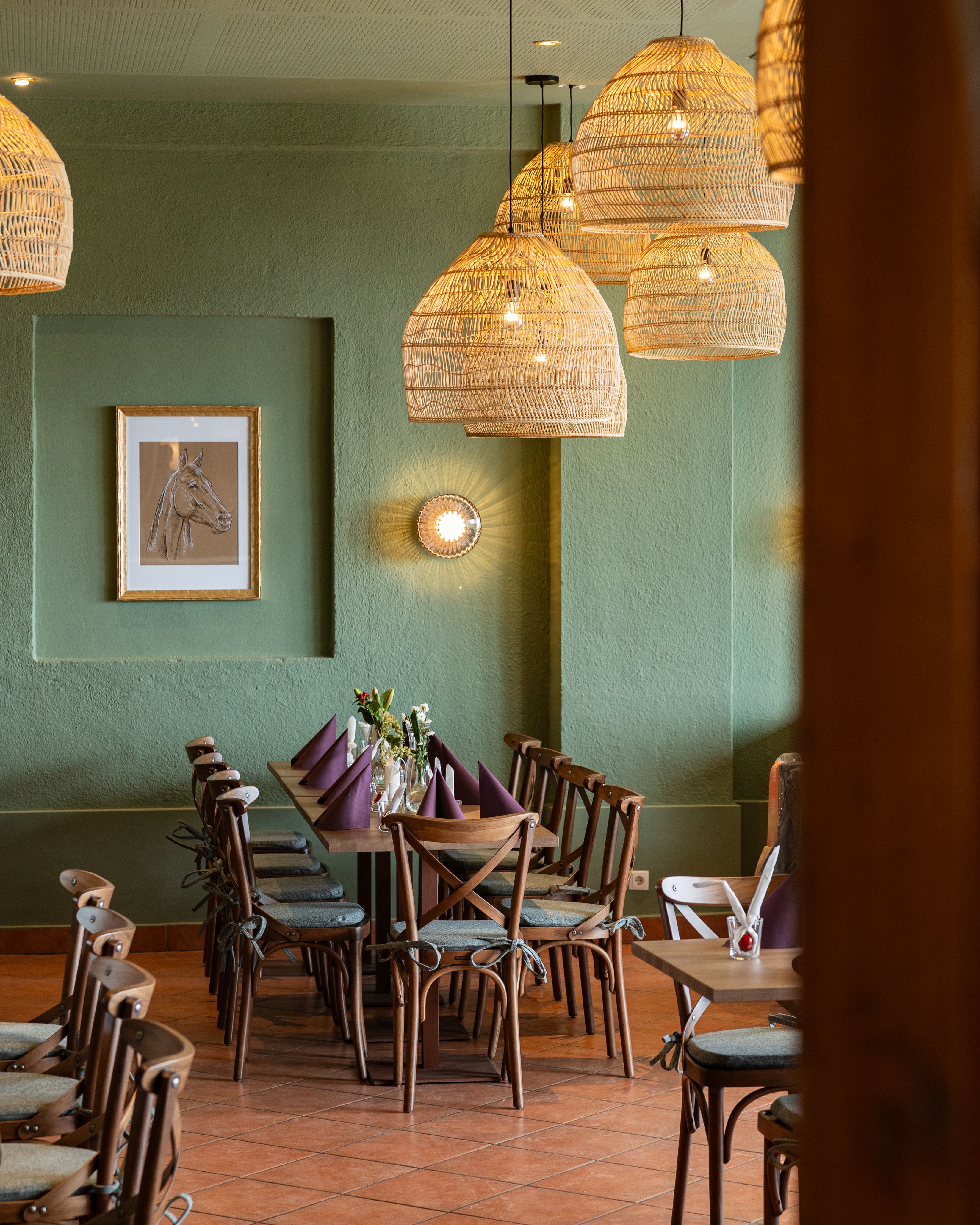 Gemütlicher Essbereich mit Holztisch, Stühlen und geflochtenen Lampen.