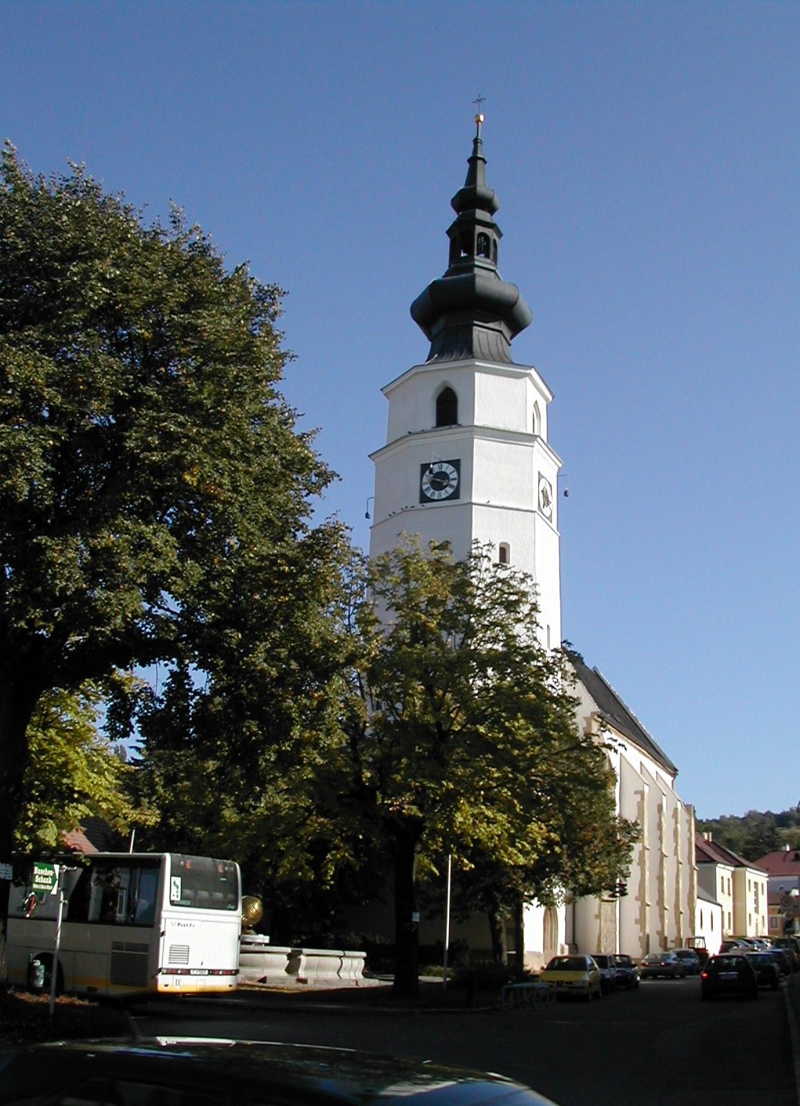 Pfarrkirche Königstetten mit Turm und Bäumen im Vordergrund.