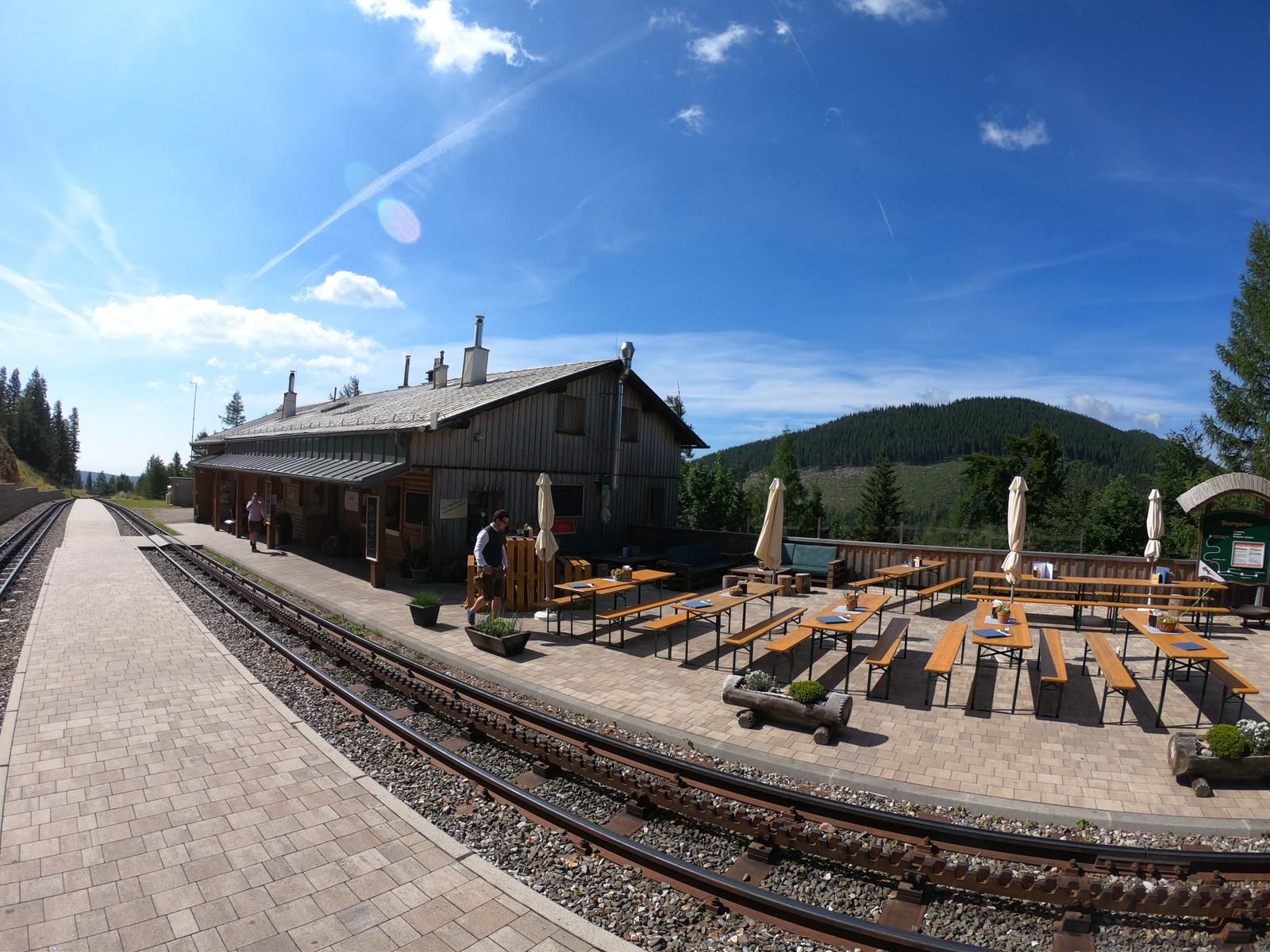 Haltestelle Baumgartner an der Schneebergbahn mit Gleisen und Sitzbereich im Freien.