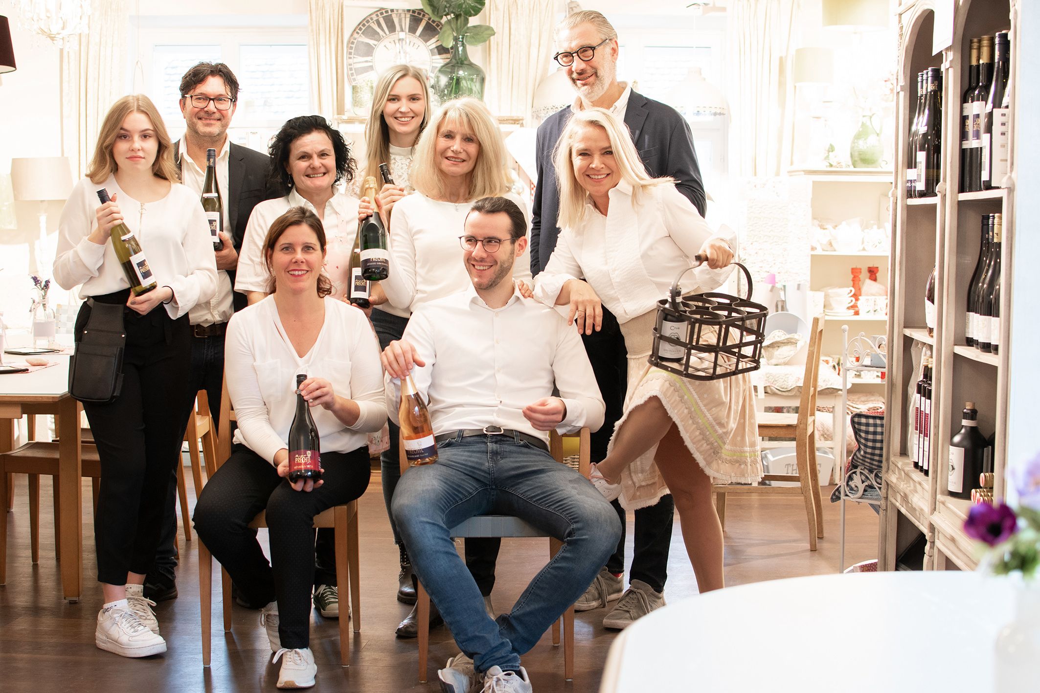 Gruppe von Menschen in einem Raum mit Weinflaschen.