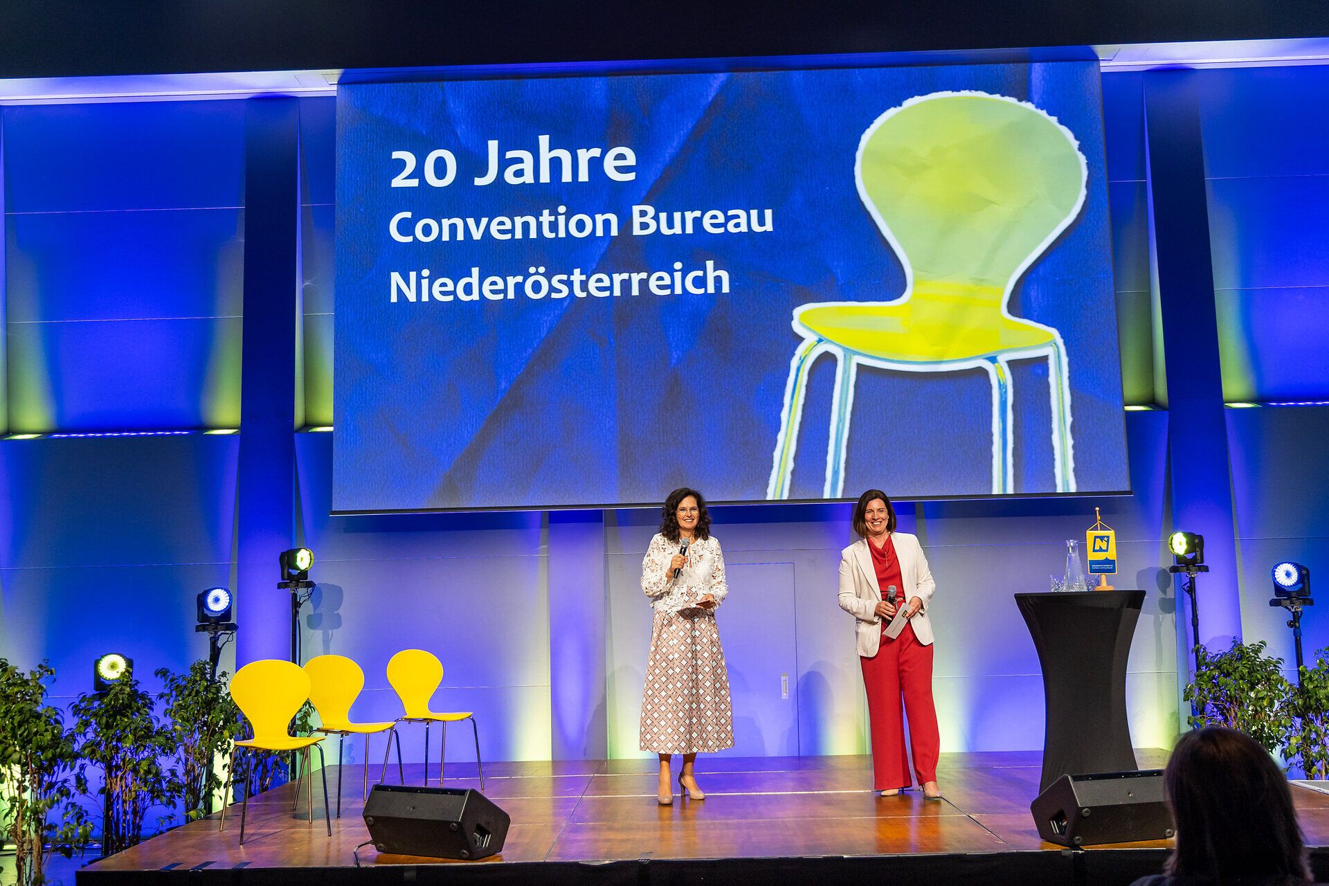 Edith Mader und Maria Luise Fröch vom Convention Bureau Niederösterreich auf der Bühne beim 20-jährigen Jubiläum, vor der Präsentation des Jubiläumsfilms.