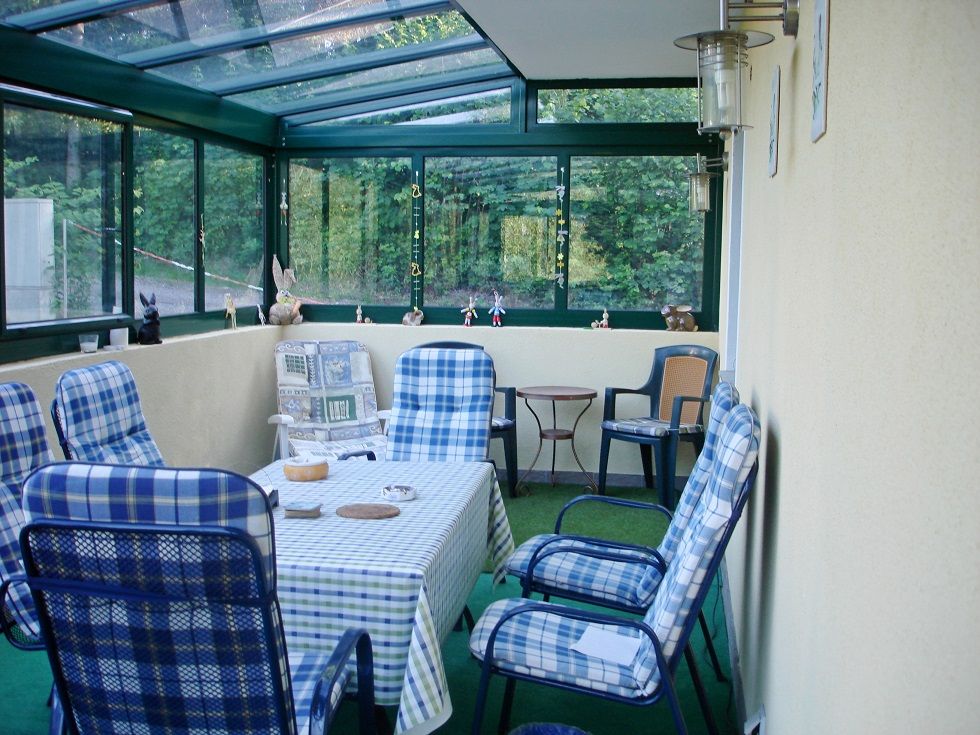 Wintergarten mit Tisch und Stühlen, dekoriert mit Figuren.