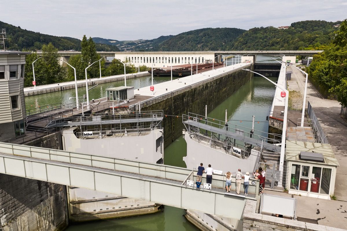 Besuchergruppe beobachtet die Einfahrt eines Schiffes in die Schleusenkammer, während der Tourguide die Funktionsweise der Schleuse erklärt.