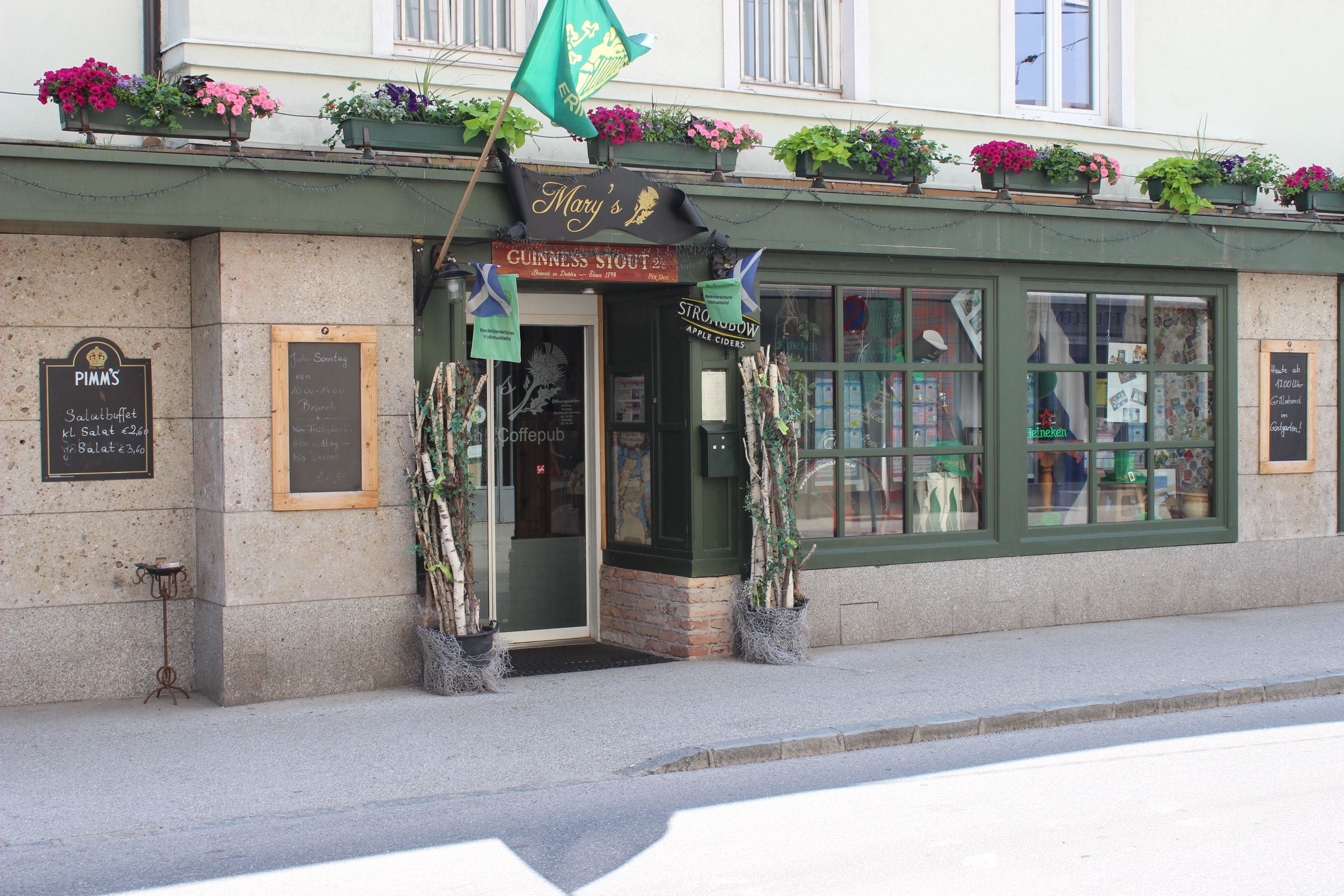 Eingang eines Pubs mit grüner Fassade und Blumenkästen.