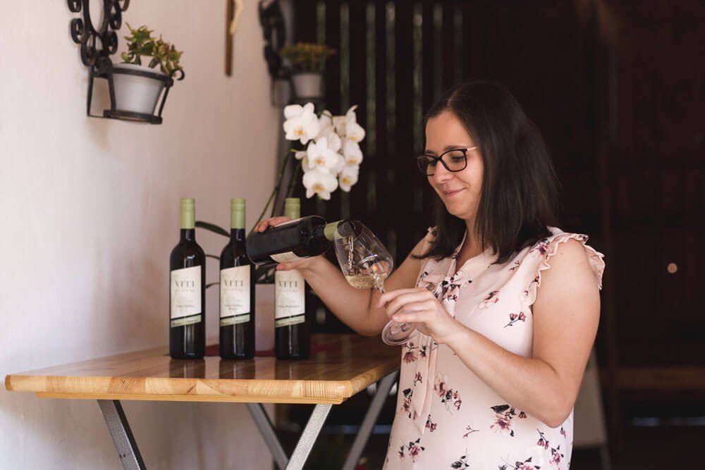 Frau schenkt Wein in ein Glas ein.