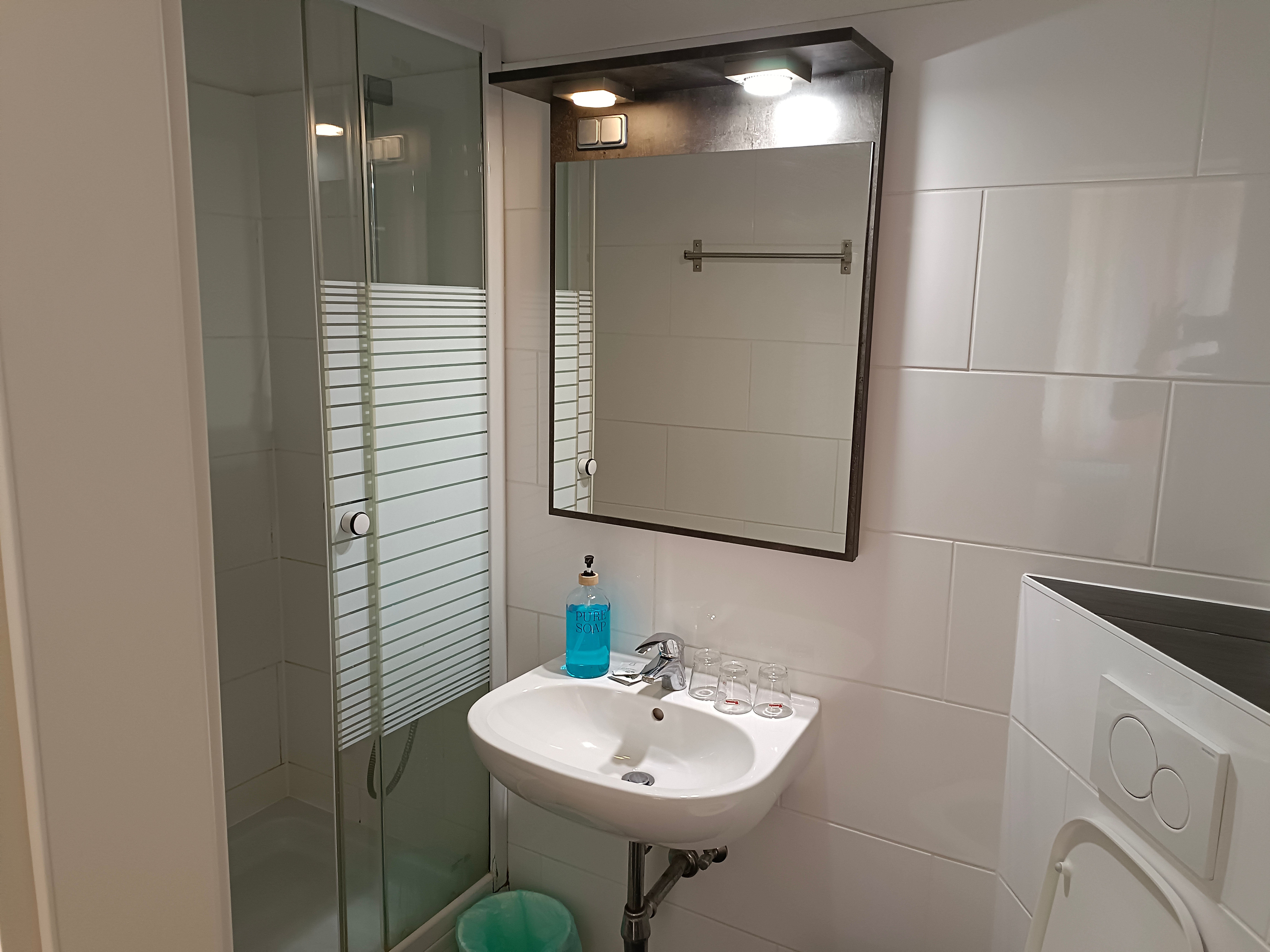 Modernes Badezimmer mit Dusche, Waschbecken und Spiegel.