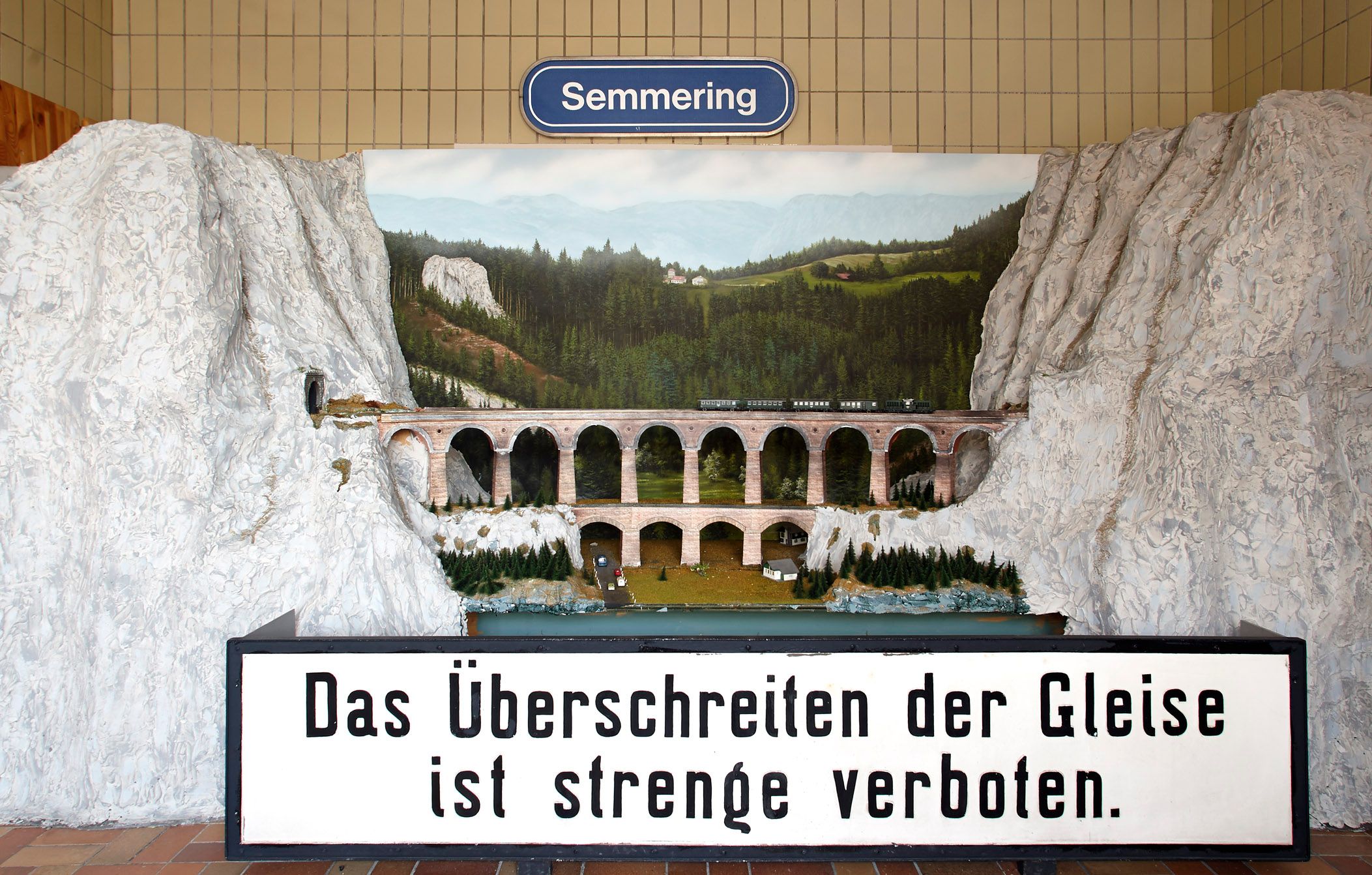 Modell des Kalte Rinne-Viadukts mit Zug und Landschaft im Hintergrund. Schild mit Aufschrift: 'Das Überschreiten der Gleise ist streng verboten.'