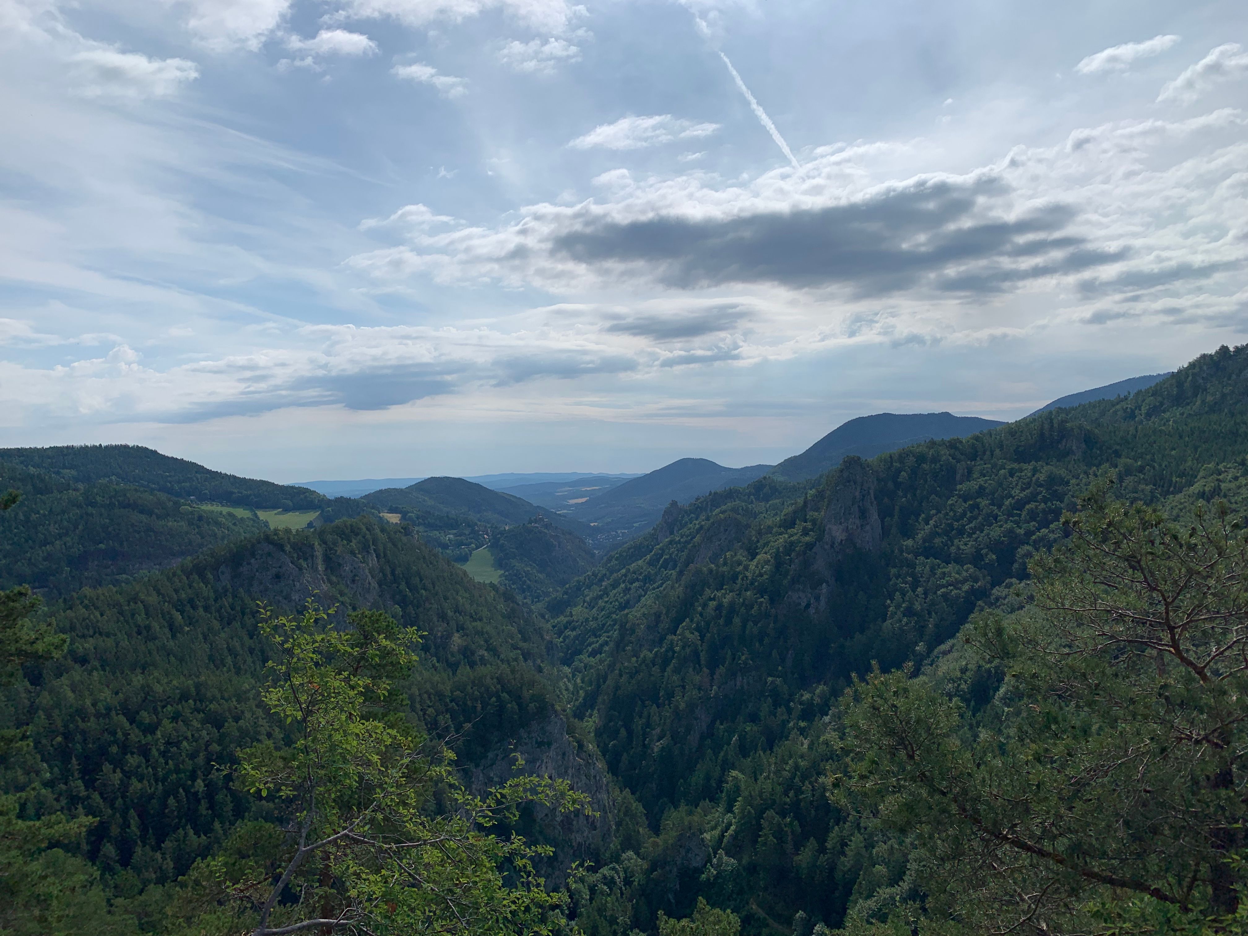 Blick auf bewaldete Berge und Täler unter einem bewölkten Himmel.
