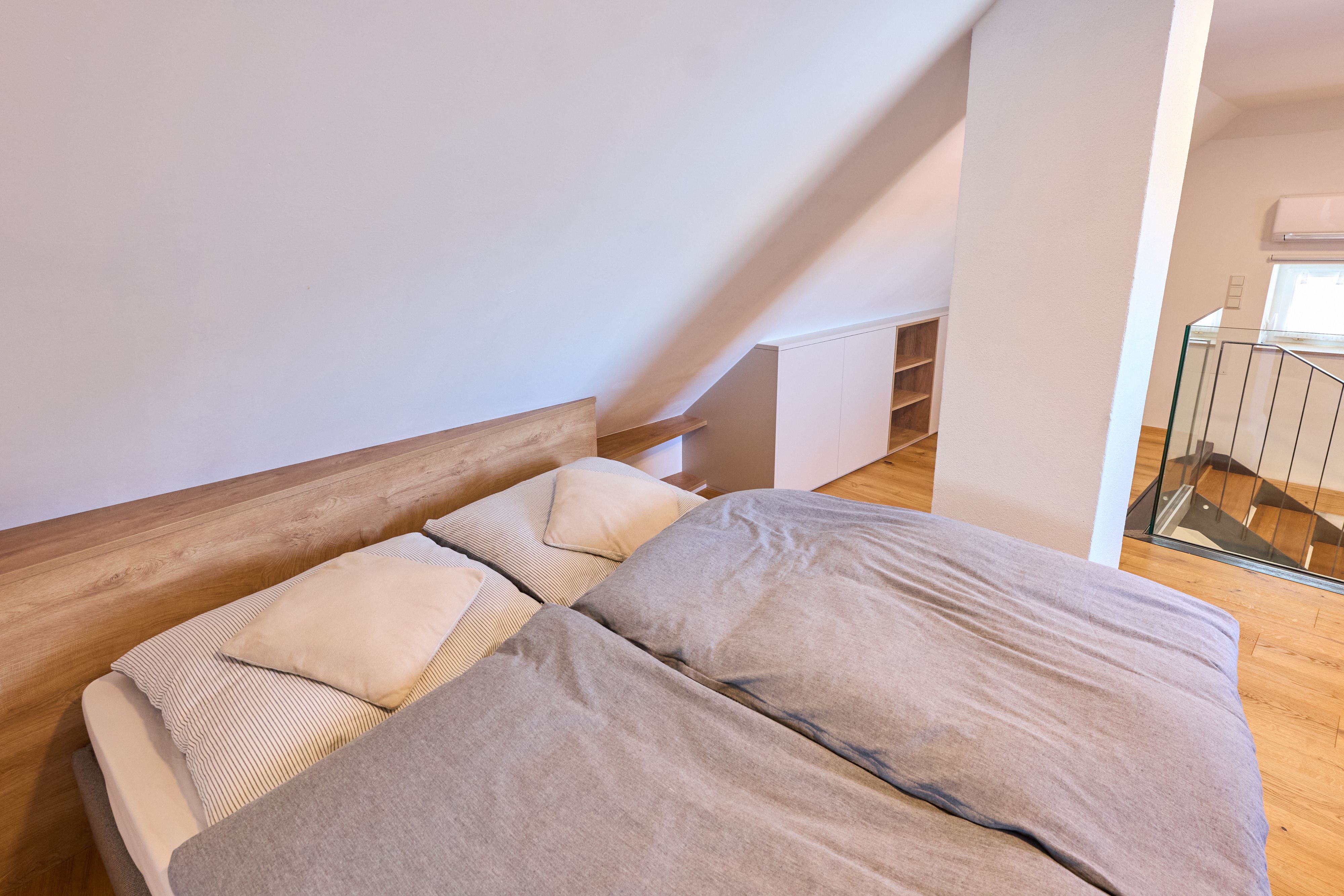 Dachgeschoss-Schlafzimmer mit Doppelbett und Holzboden.