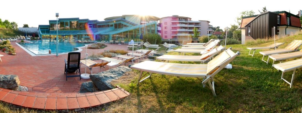 Ein Poolbereich mit Liegestühlen und einem modernen Gebäude im Hintergrund.