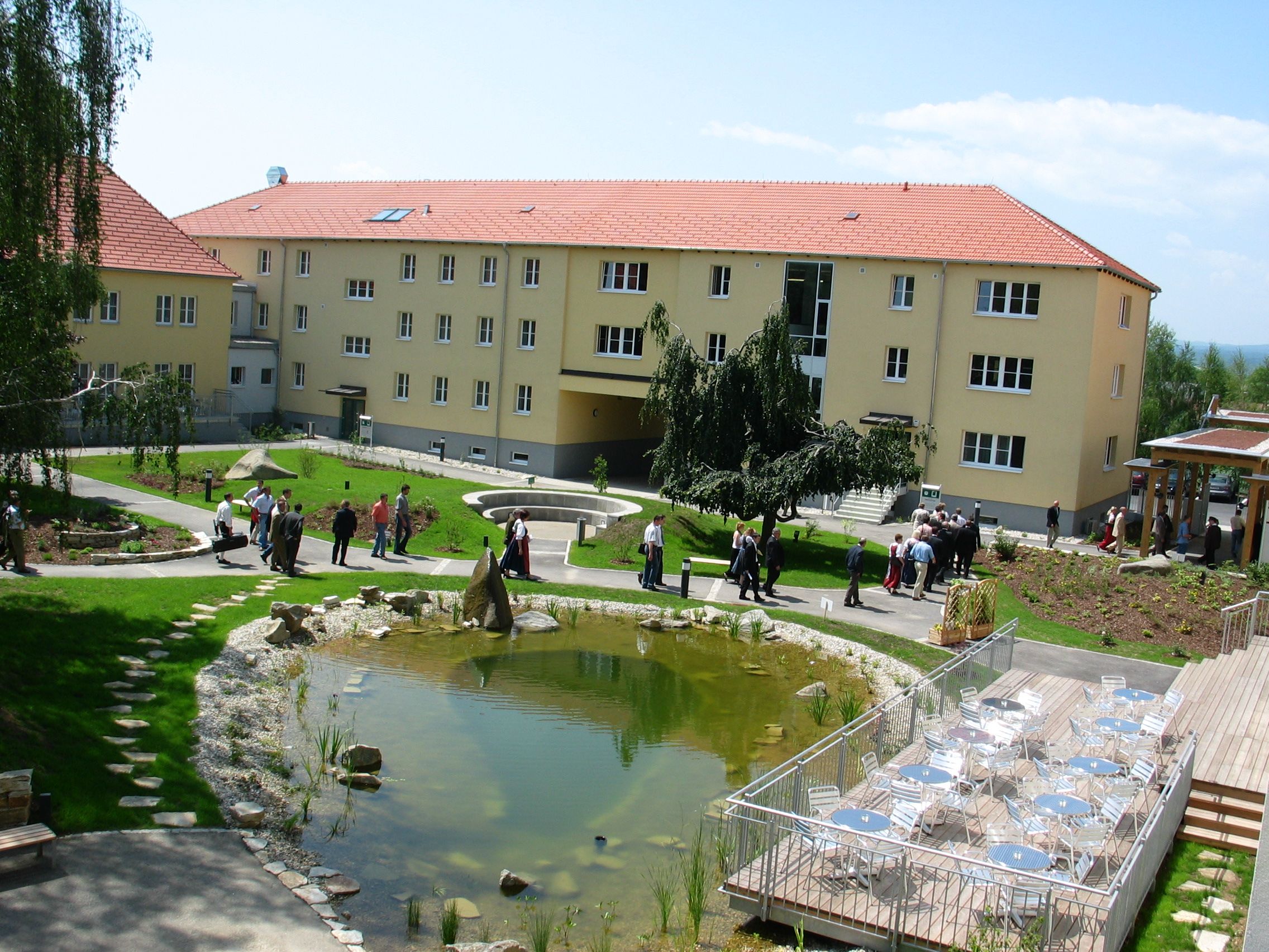 Innenhof mit Teich, Sitzbereich und Menschen.