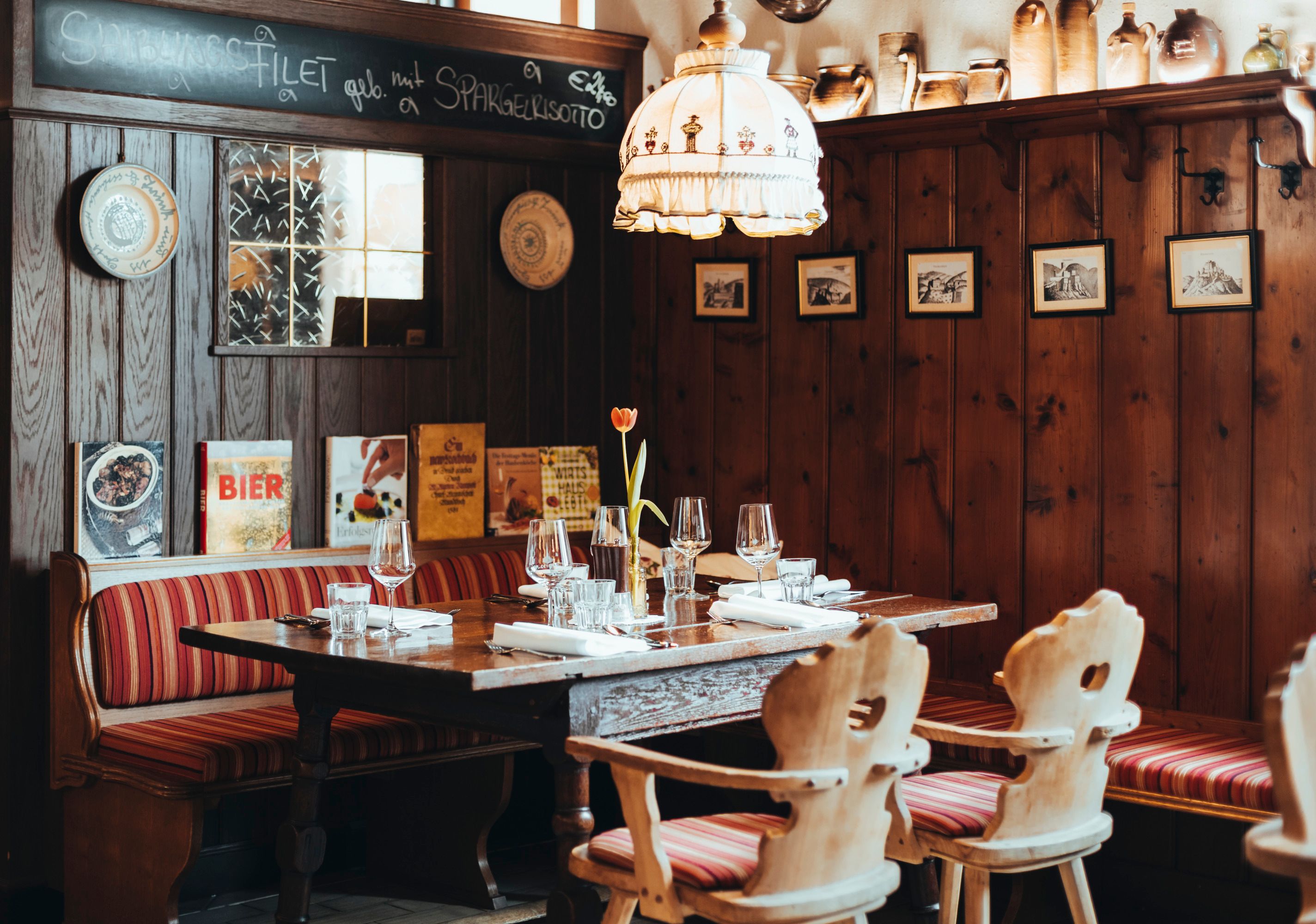 Gemütliches Restaurant mit Holzwänden, rot gestreiften Sitzbänken und gedecktem Tisch.
