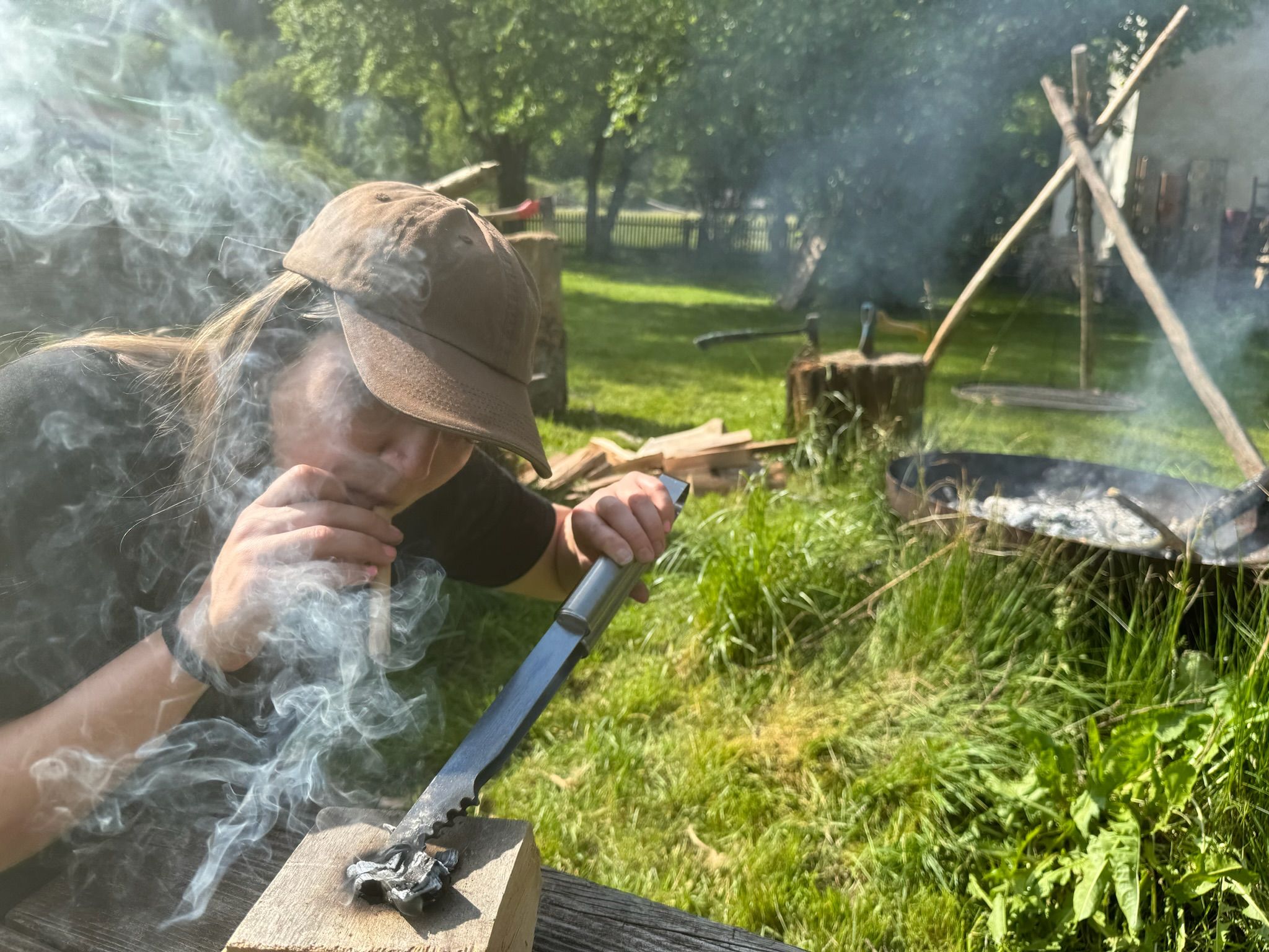 Person entzündet Feuer mit Messer und Holz im Freien.