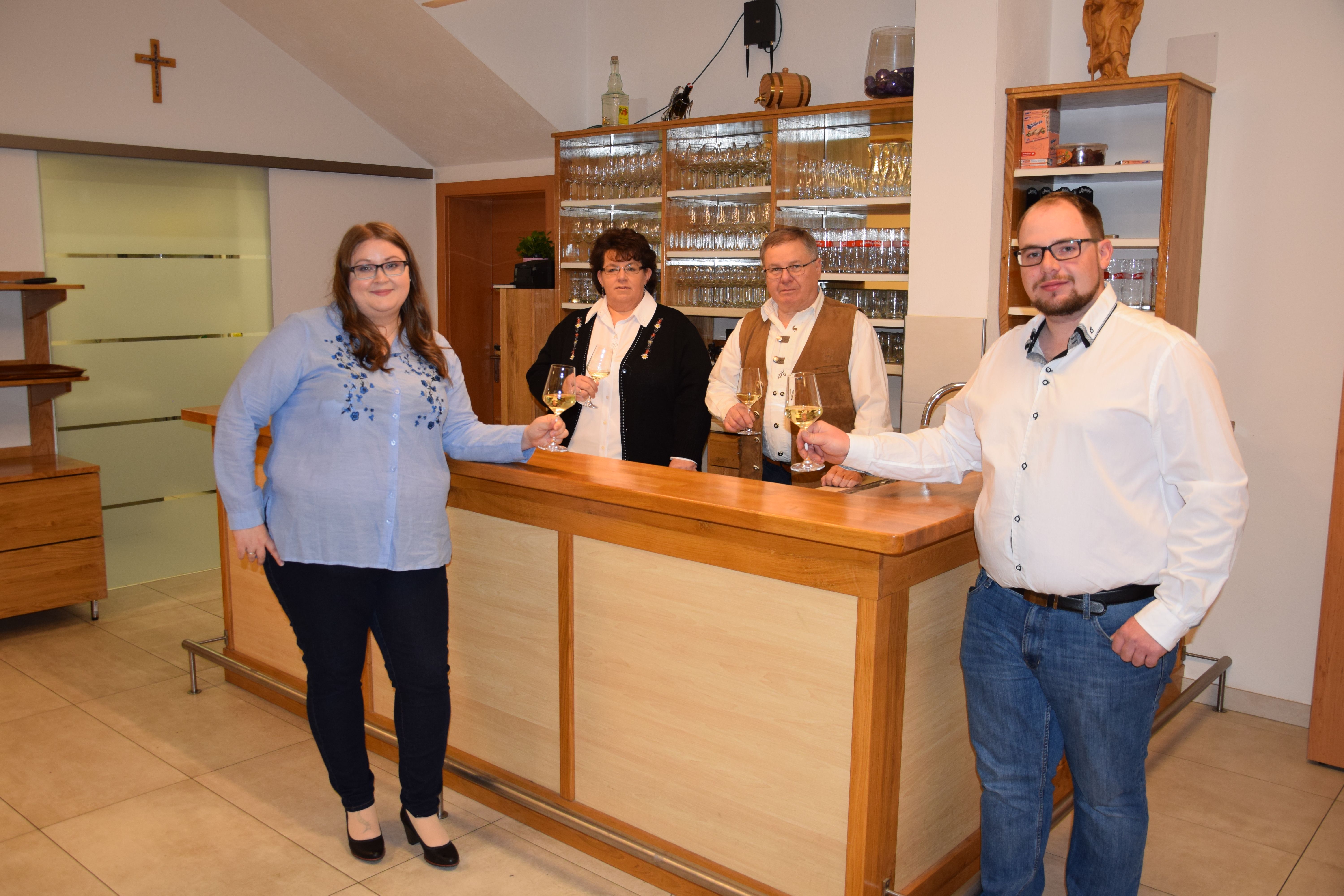 Vier Personen stehen an einer Theke und halten Weingläser in der Hand.