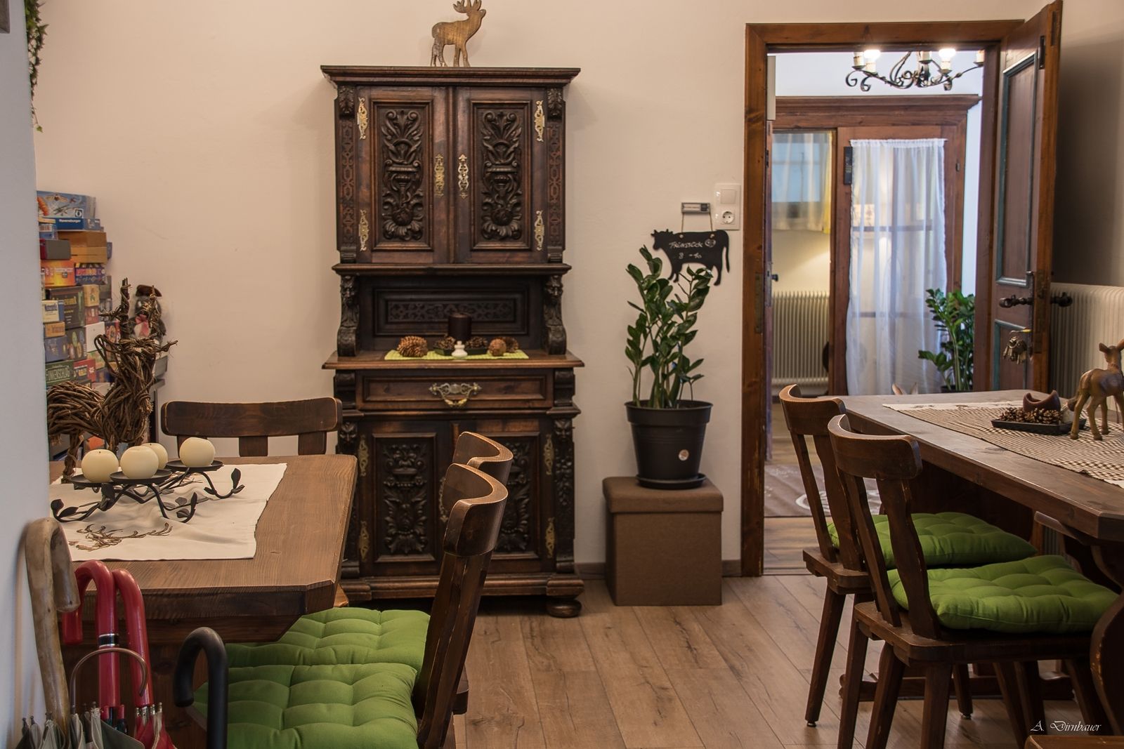 Gemütlicher Aufenthaltsraum mit Holzmöbeln, grünen Sitzkissen und dekorativem Schrank.