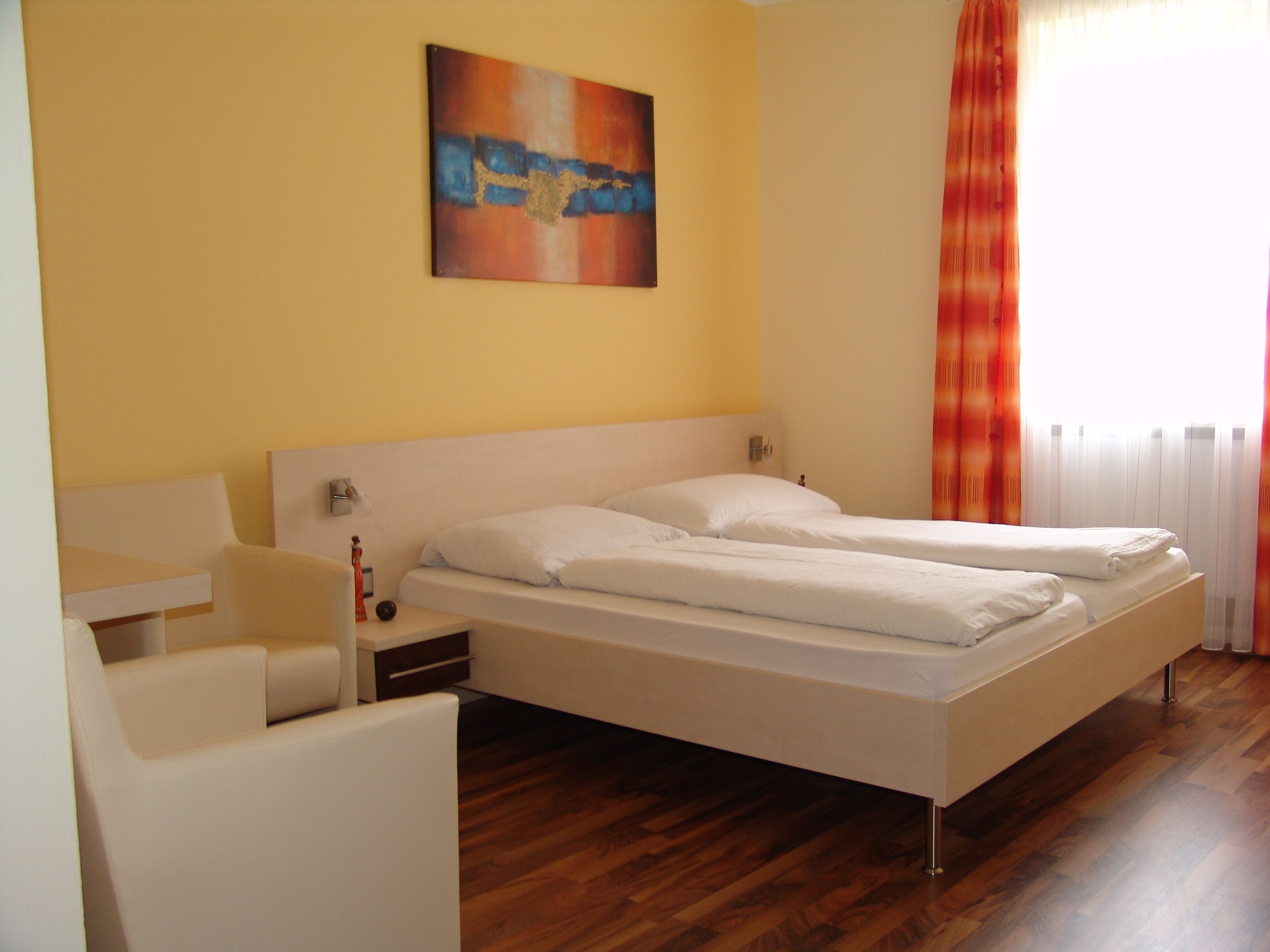 Ein modernes Hotelzimmer mit Doppelbett, gelben Wänden und einem abstrakten Gemälde.