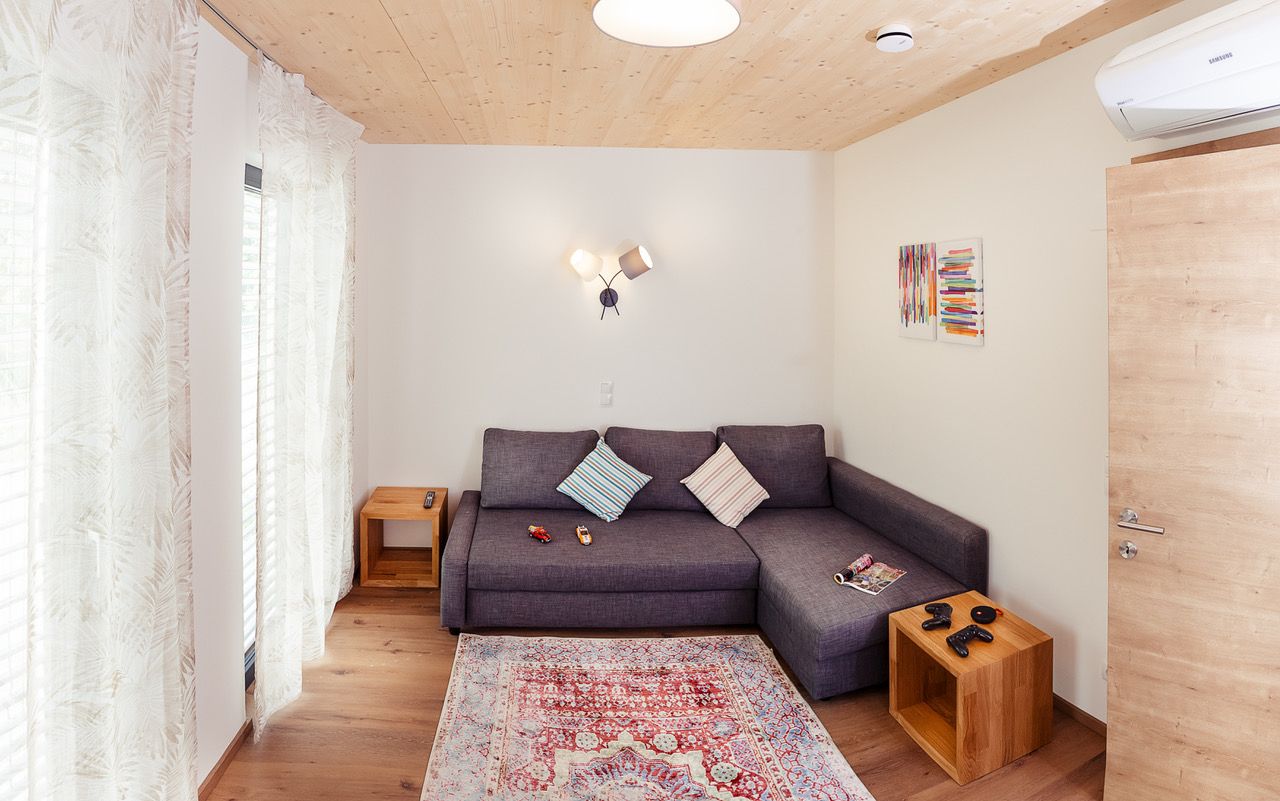 Modernes Wohnzimmer mit grauem Sofa, Holzboden und bunter Wandkunst.