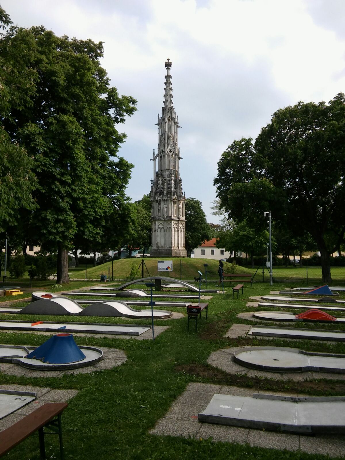 Minigolfplatz mit gotischem Denkmal im Hintergrund.