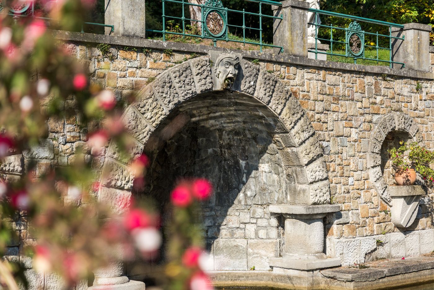 Steinbrunnen mit Wasserspeier in Form eines Gesichts im Schlosspark.