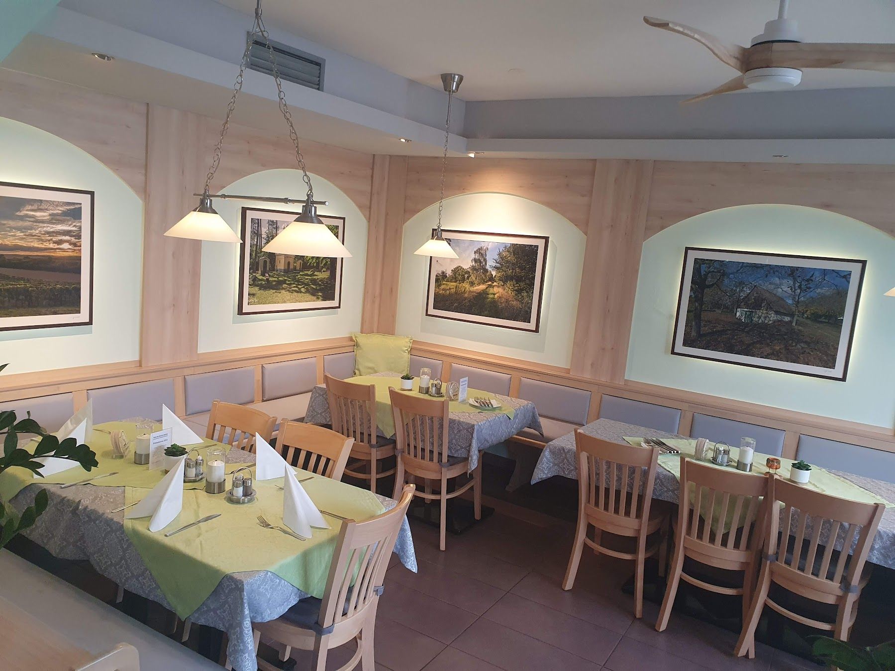Innenansicht eines Restaurants mit Holzmöbeln und dekorativen Bildern an der Wand.