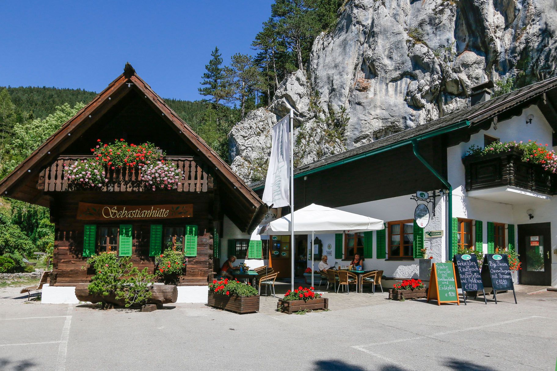 Ein traditionelles Gasthaus mit Holzbalkon und Blumenschmuck vor einer Felswand.