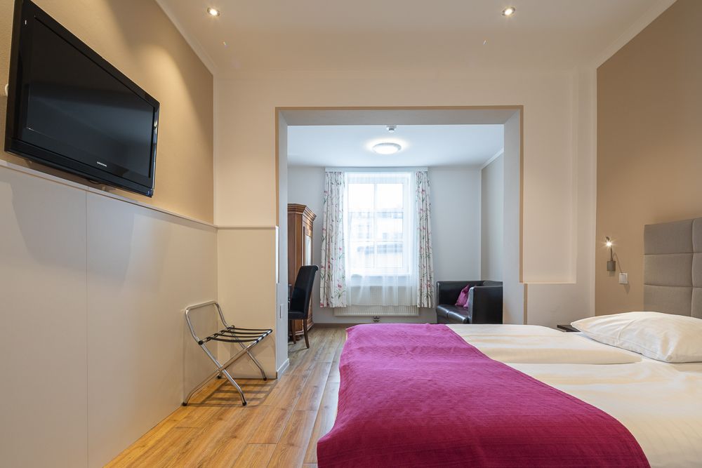 Hotelzimmer mit Doppelbett, Fernseher und Sitzbereich.