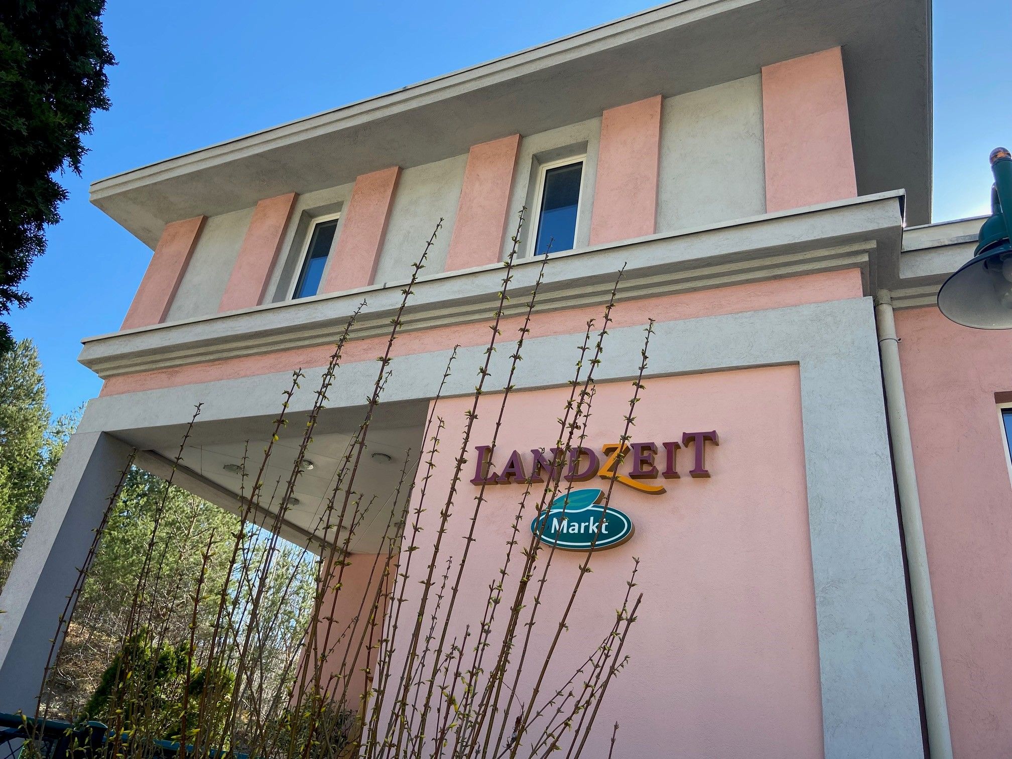 Gebäude mit rosa und grauer Fassade, Schriftzug 'Landzeit Markt'.