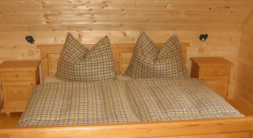 Holzschlafzimmer mit kariertem Doppelbett und Nachttischen.