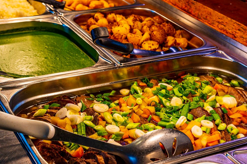 Buffet mit verschiedenen Speisen in Edelstahlbehältern.